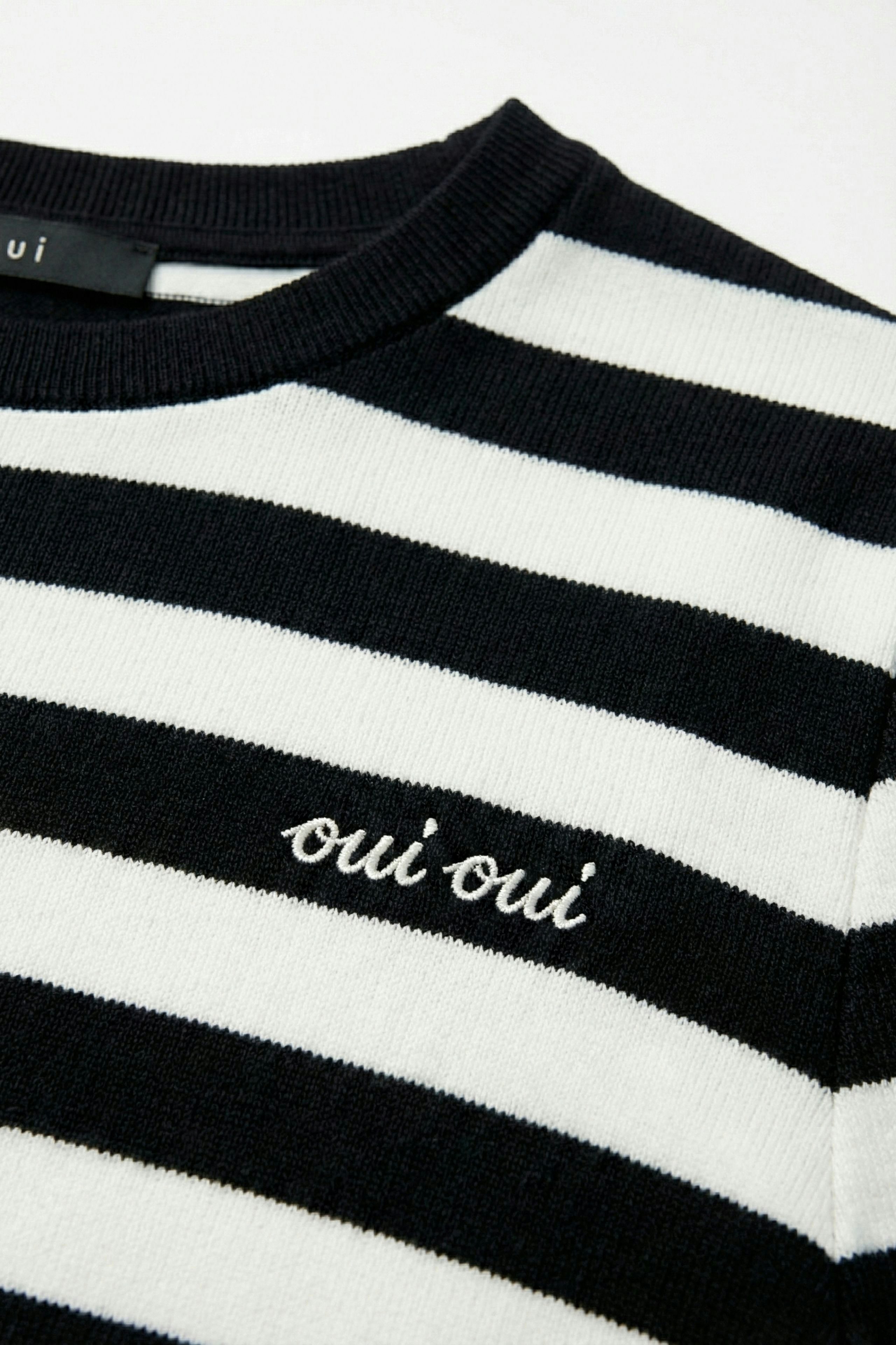 Casual women's T-shirt: Close-up of a black and white striped shirt with 'oui oui' embroidery.
