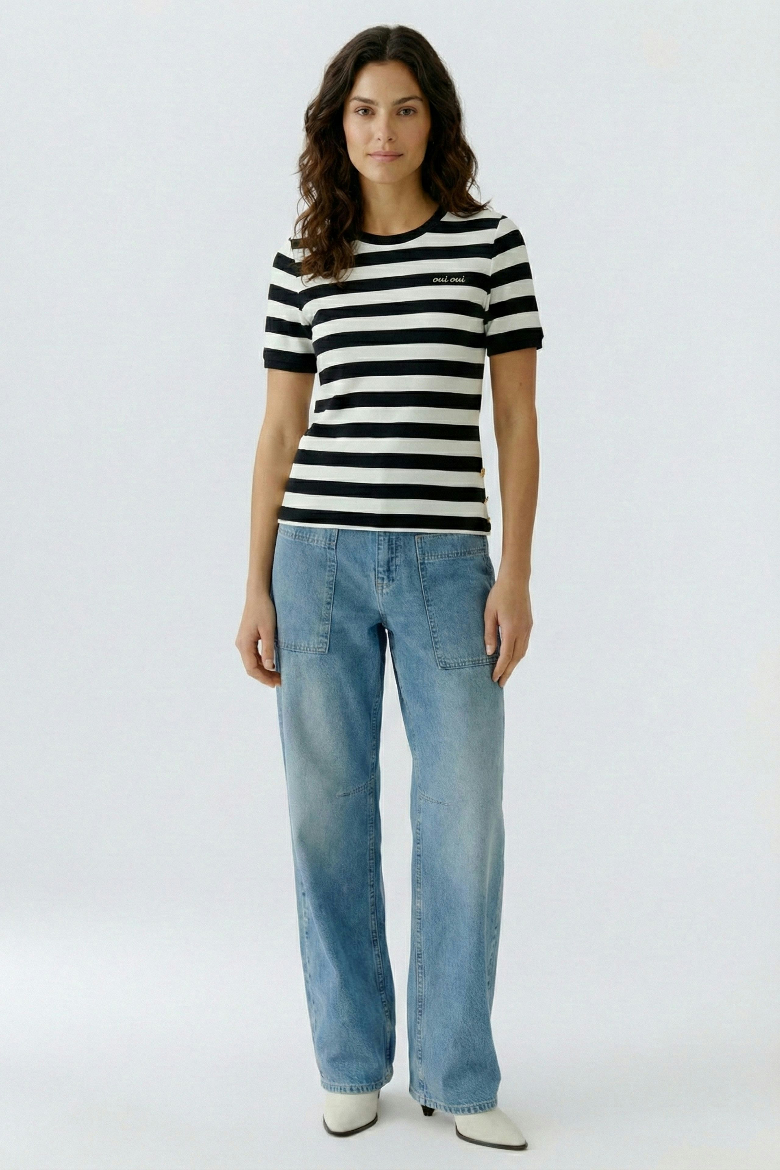 Casual women's T-shirt: Woman in a black and white striped tee paired with relaxed-fit jeans.