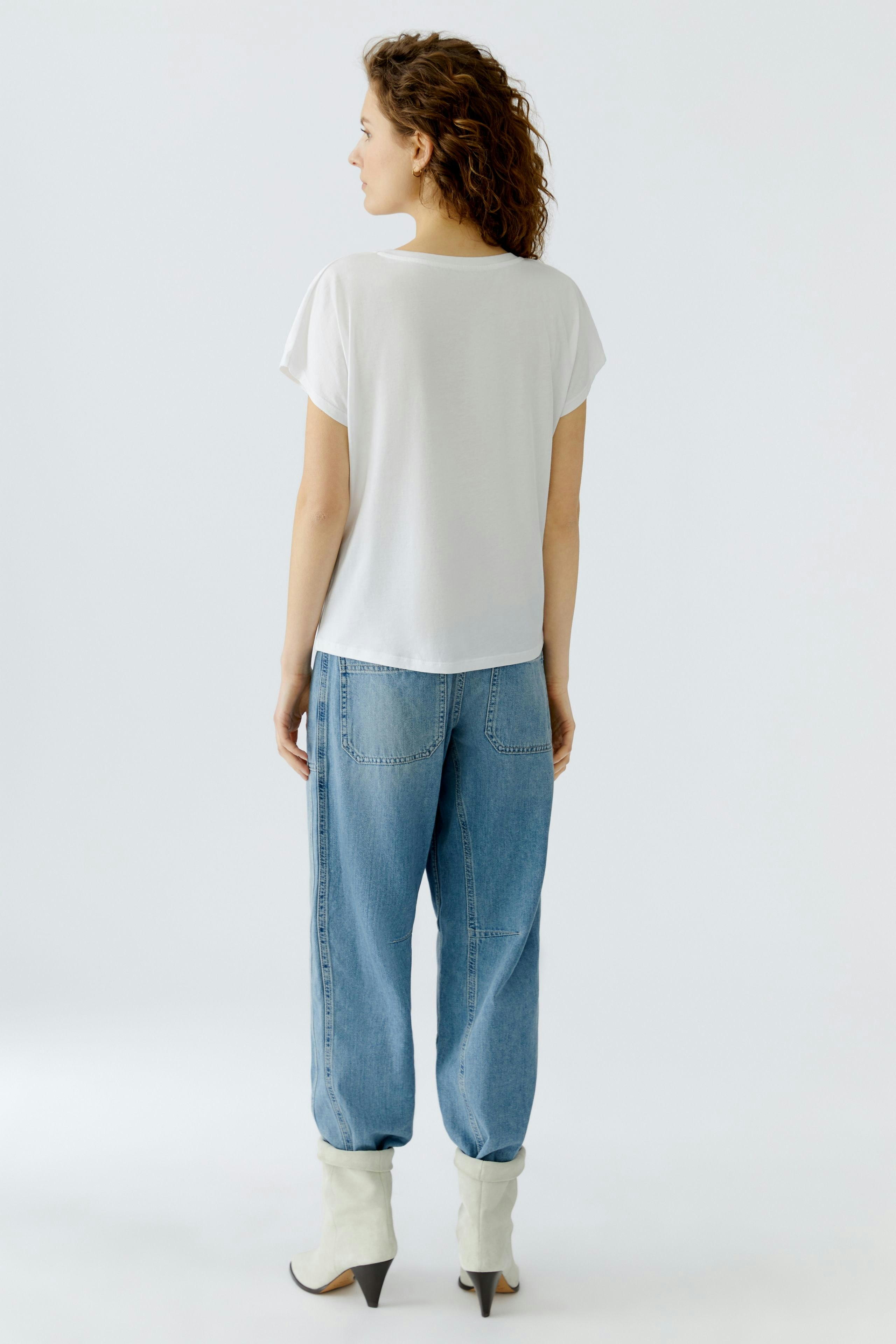 Casual women's T-shirt: A woman in a white T-shirt and relaxed jeans, showcasing a laid-back style.
