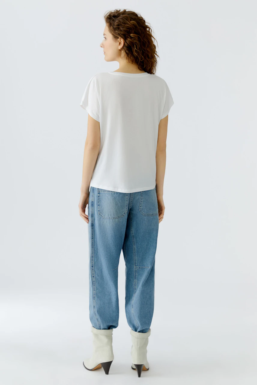 Casual women's T-shirt: A woman in a white T-shirt and relaxed jeans, showcasing a laid-back style.