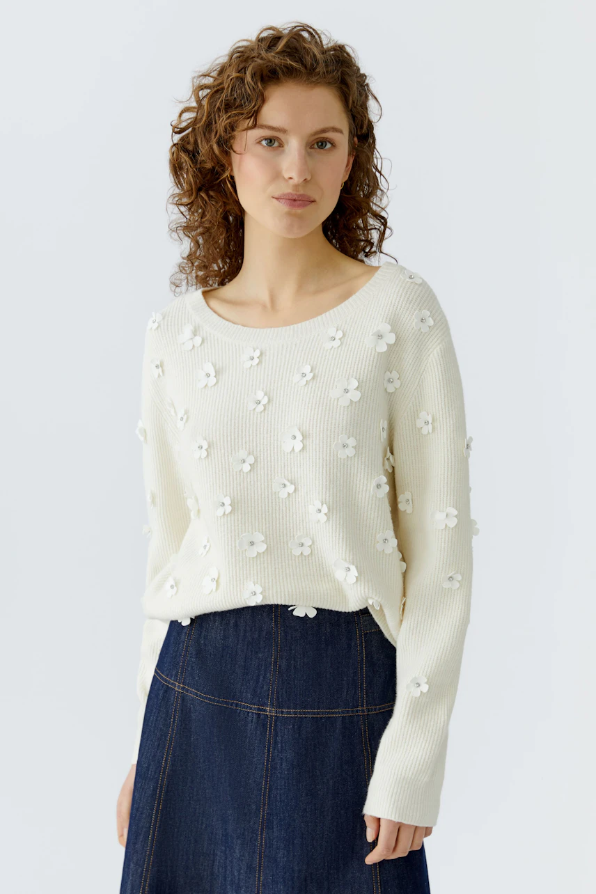 Damen-Pullover in Creme mit Blumenapplikationen, lässig kombiniert mit einem Jeansrock.
