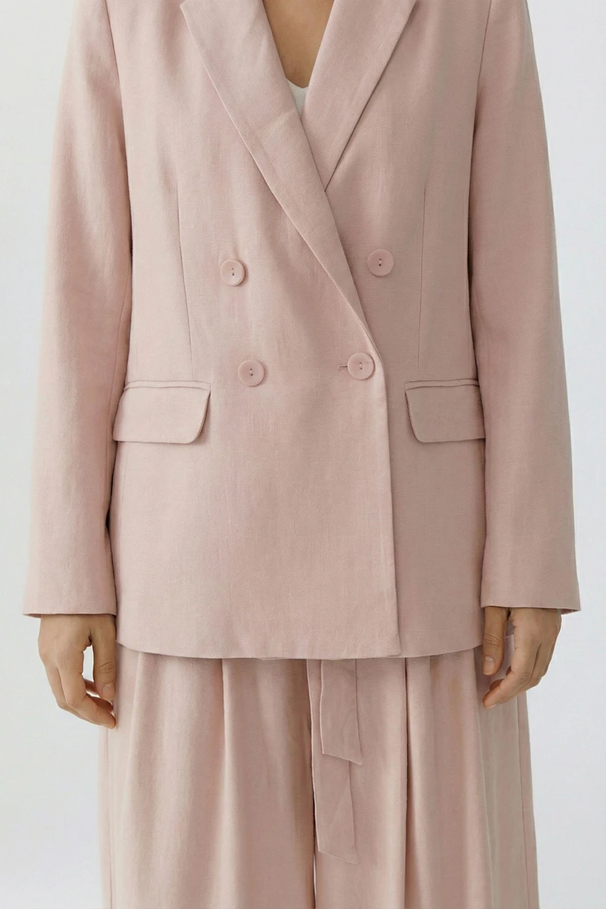 Stylish women's blazer in soft pink with double-breasted buttons, paired with matching trousers.