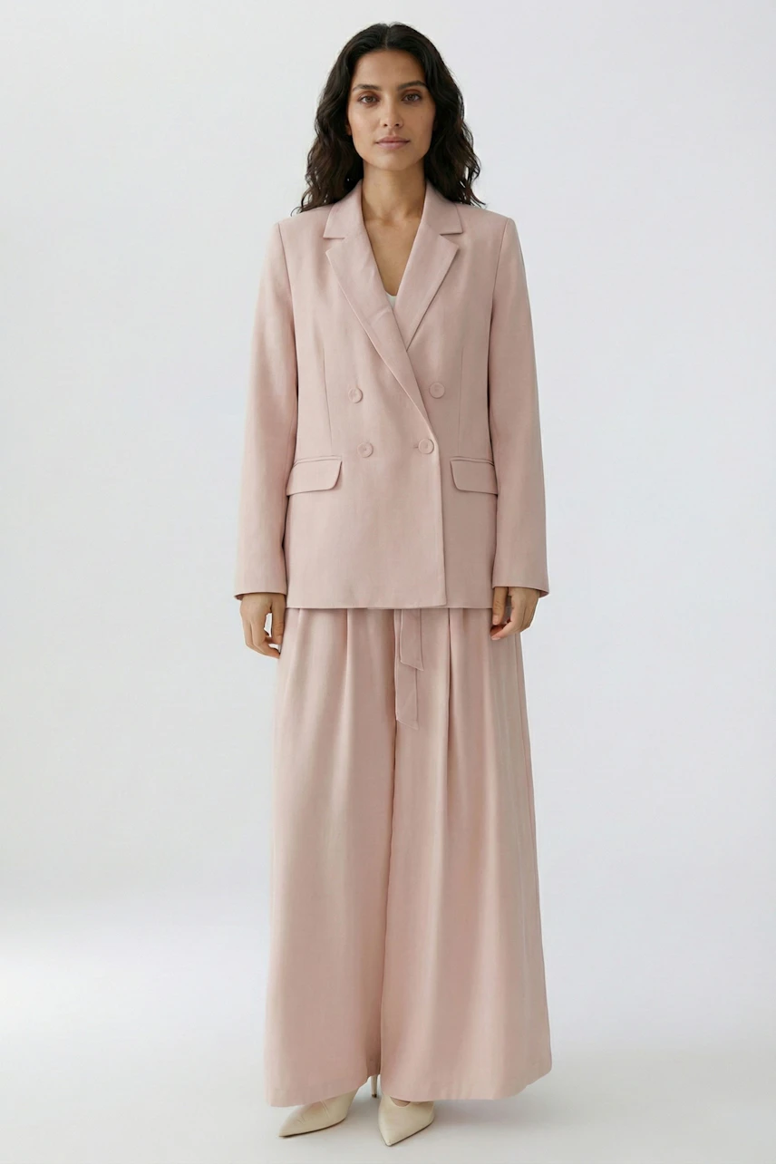 Stylish women's blazer: A woman in a light pink double-breasted blazer paired with wide-leg trousers.