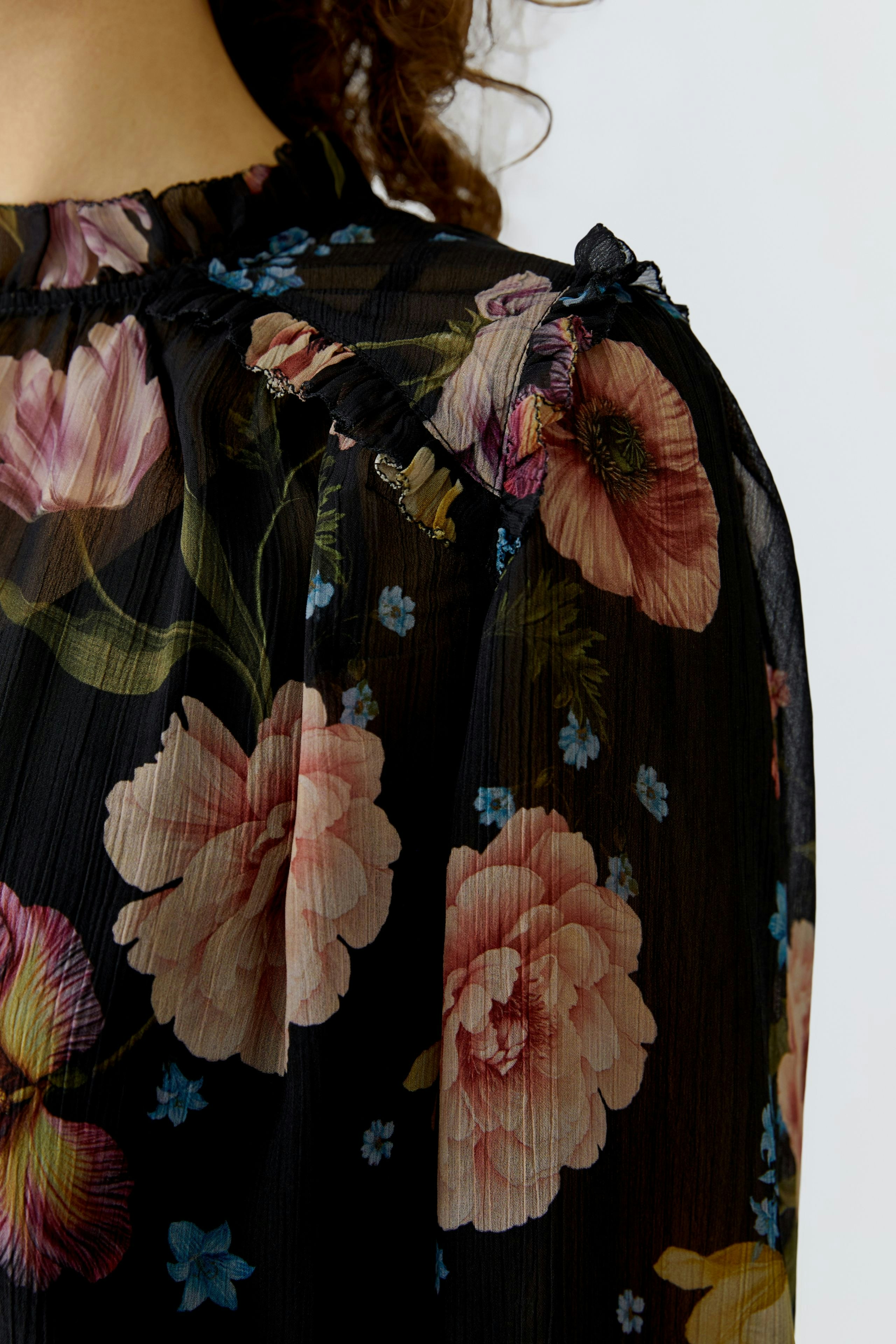 Floral blouse: Close-up of a woman's black blouse with colorful floral patterns and ruffled details.