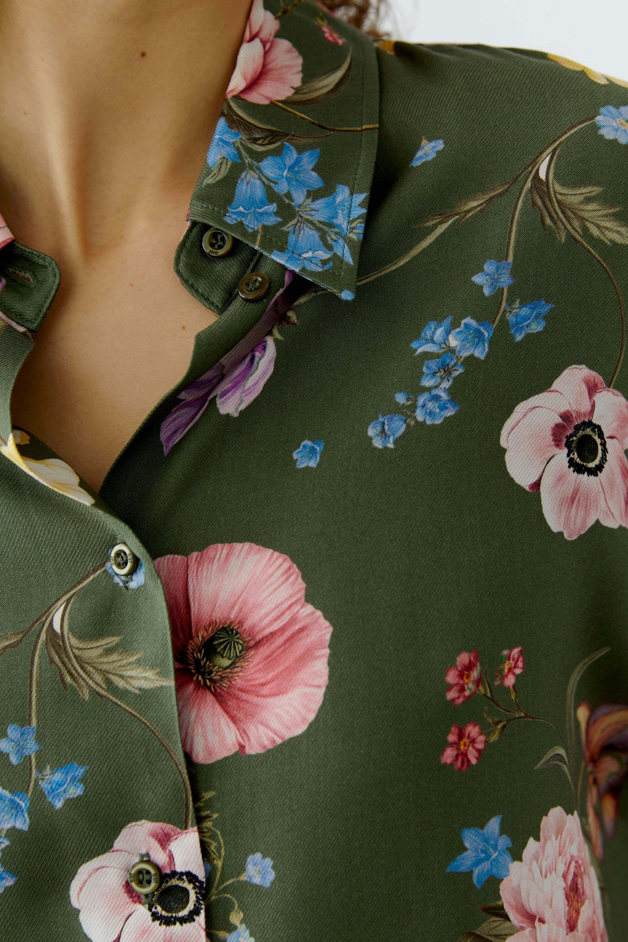 Floral blouse: Close-up of a woman wearing a green blouse with pink and blue flowers.