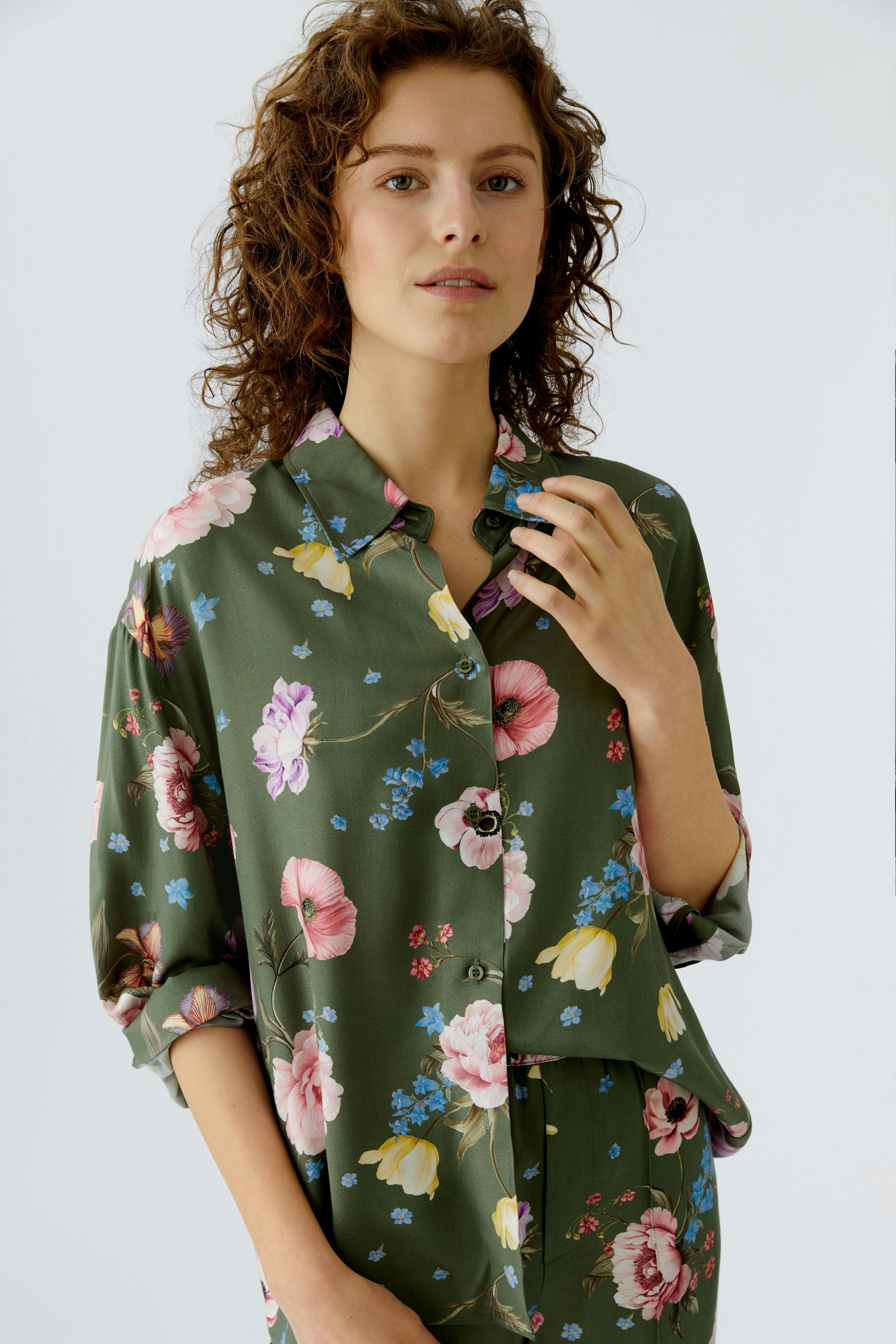 Floral blouse: Woman in a green blouse with colorful flowers, styled casually.