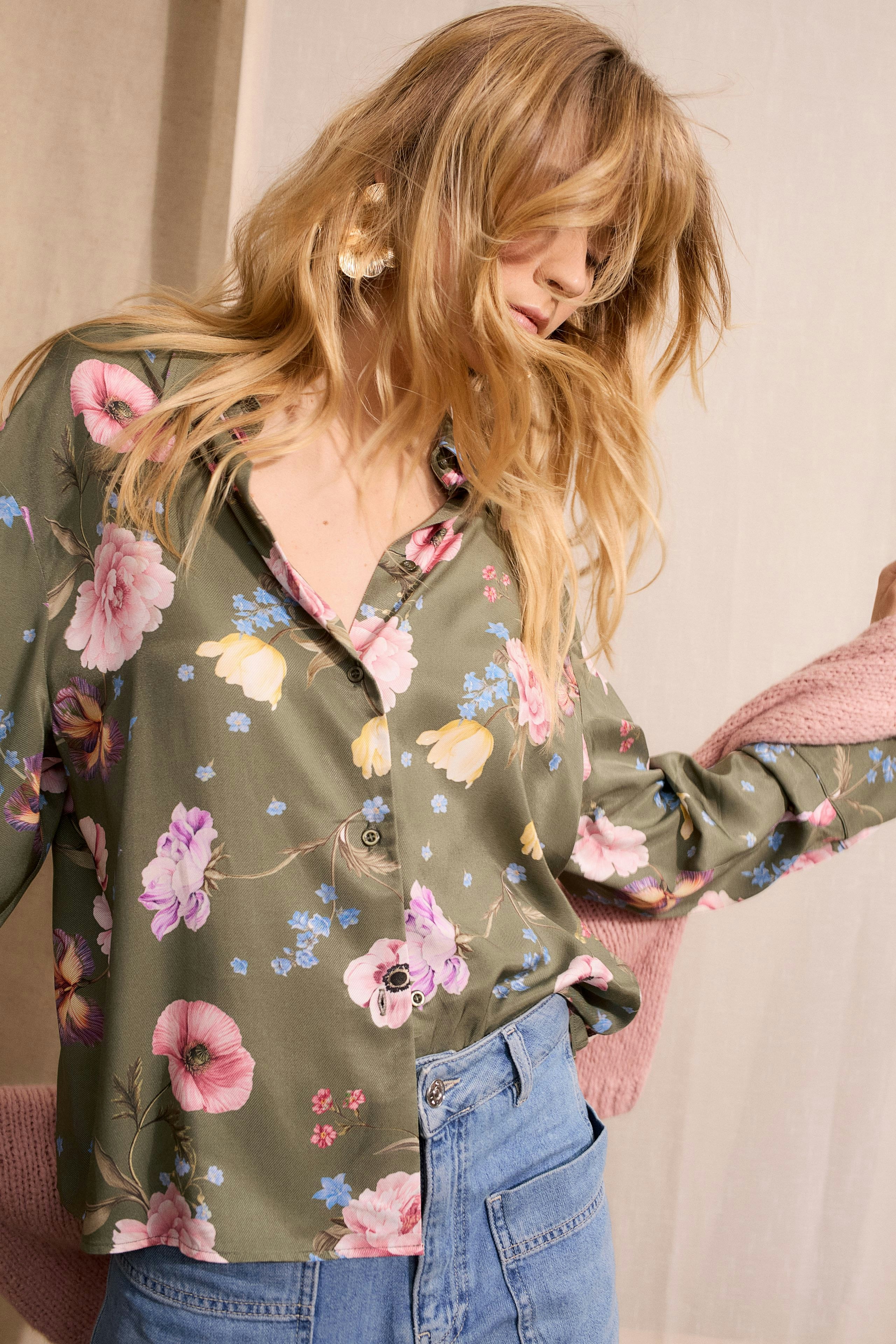 Floral blouse: Woman in a green blouse with pink and blue flowers, styled casually with denim.