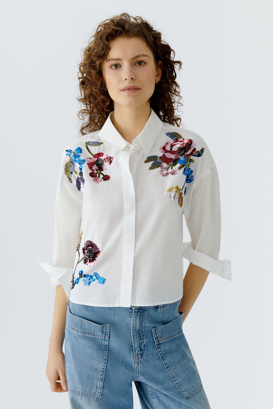Moderne Damen-Bluse: Weiße Bluse mit bunten Blumenstickereien und klassischem Kragen.