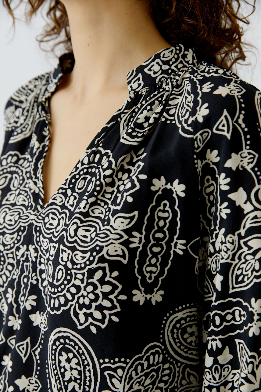 Stylish women's blouse with a black and white pattern, featuring a relaxed collar and a comfortable fit.