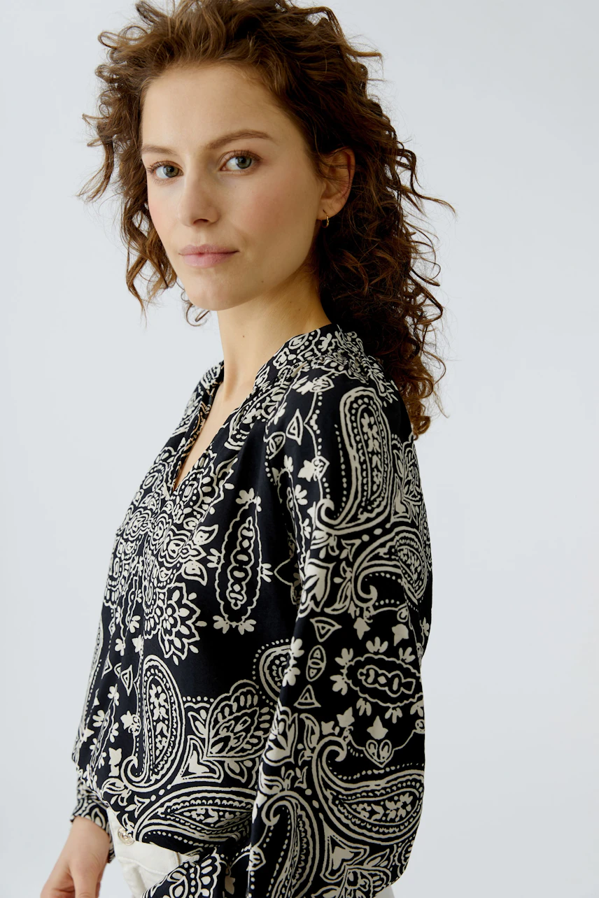 Stylish women's blouse: A woman in a black and white patterned blouse with a relaxed fit.