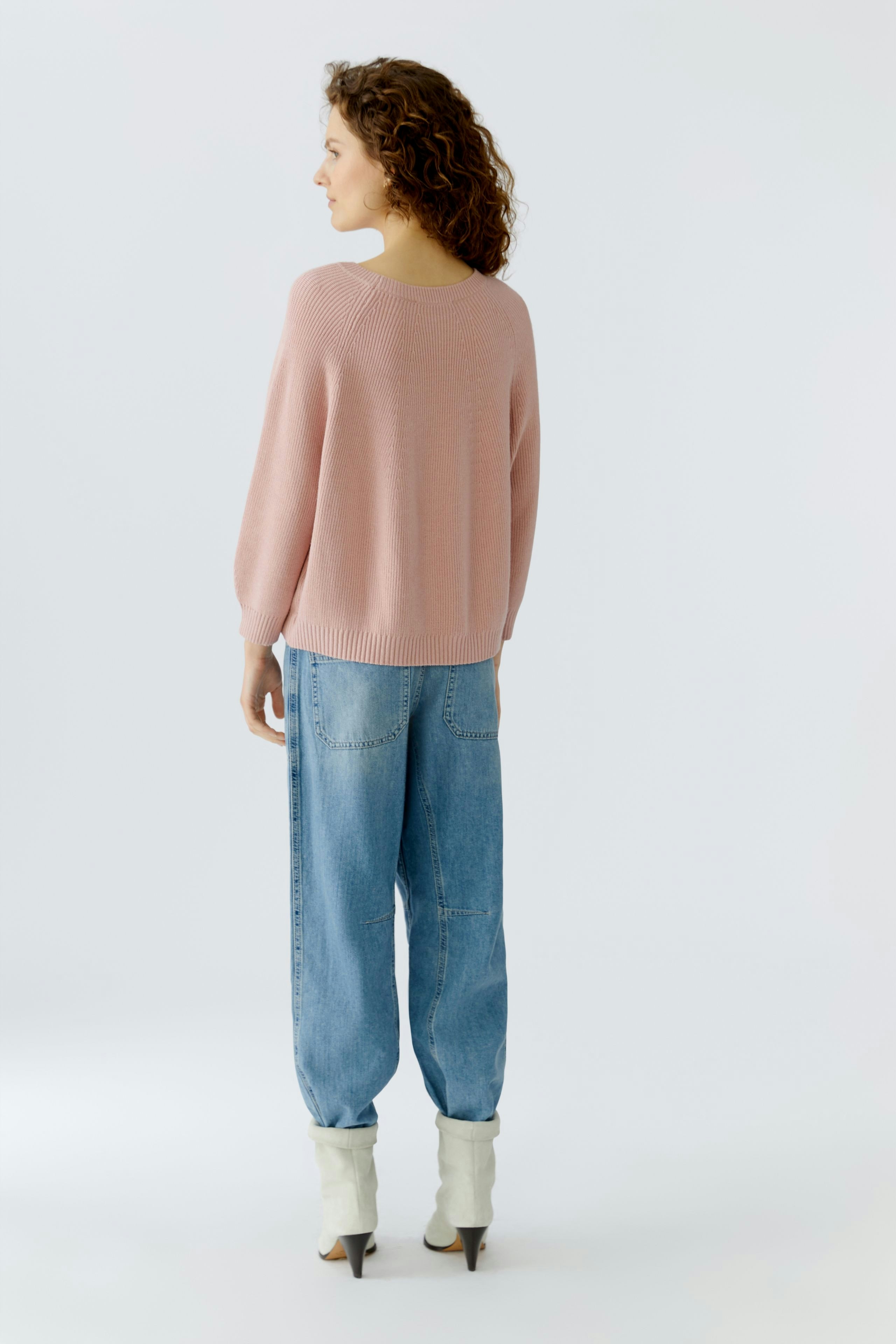 Casual women's pullover: A woman in a soft pink pullover with balloon sleeves and relaxed jeans.