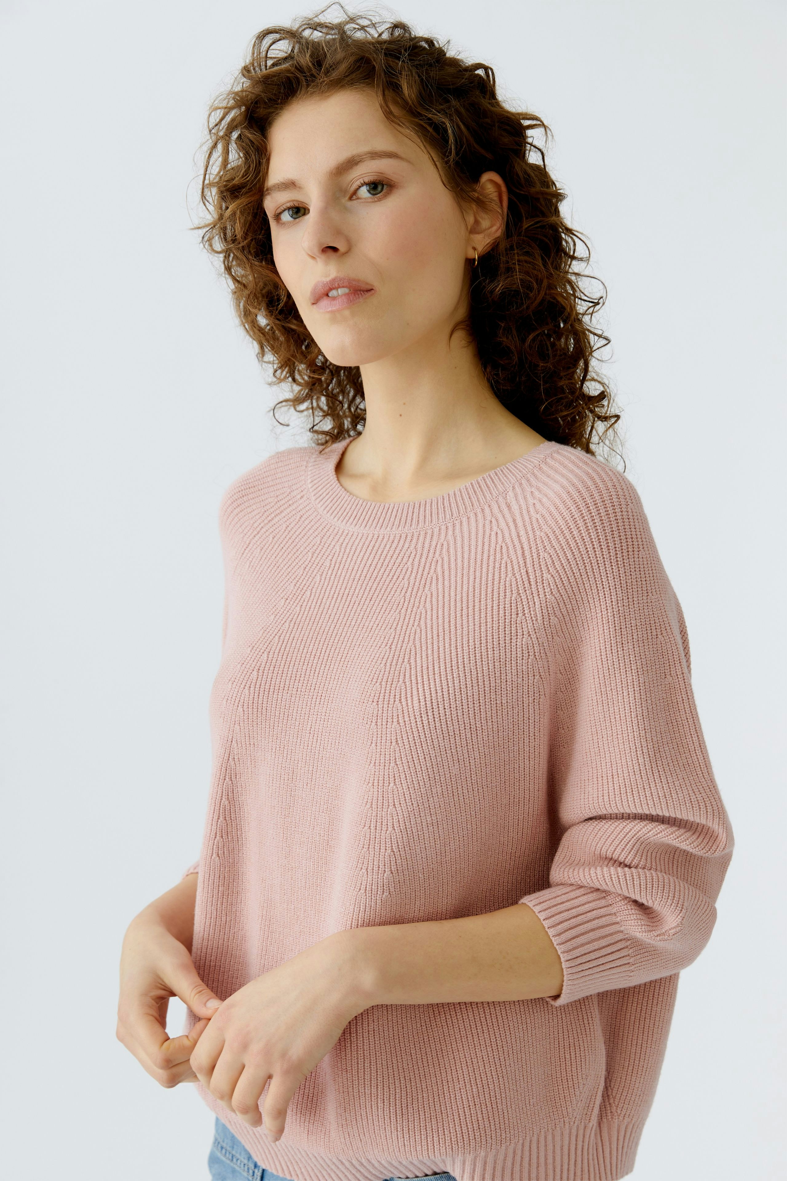 Casual women's pullover: Young woman in a soft pink knit pullover with three-quarter sleeves.
