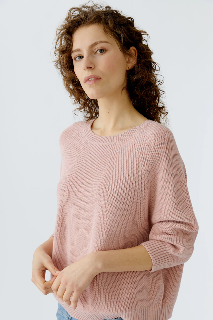 Casual women's pullover: Young woman in a soft pink knit pullover with three-quarter sleeves.