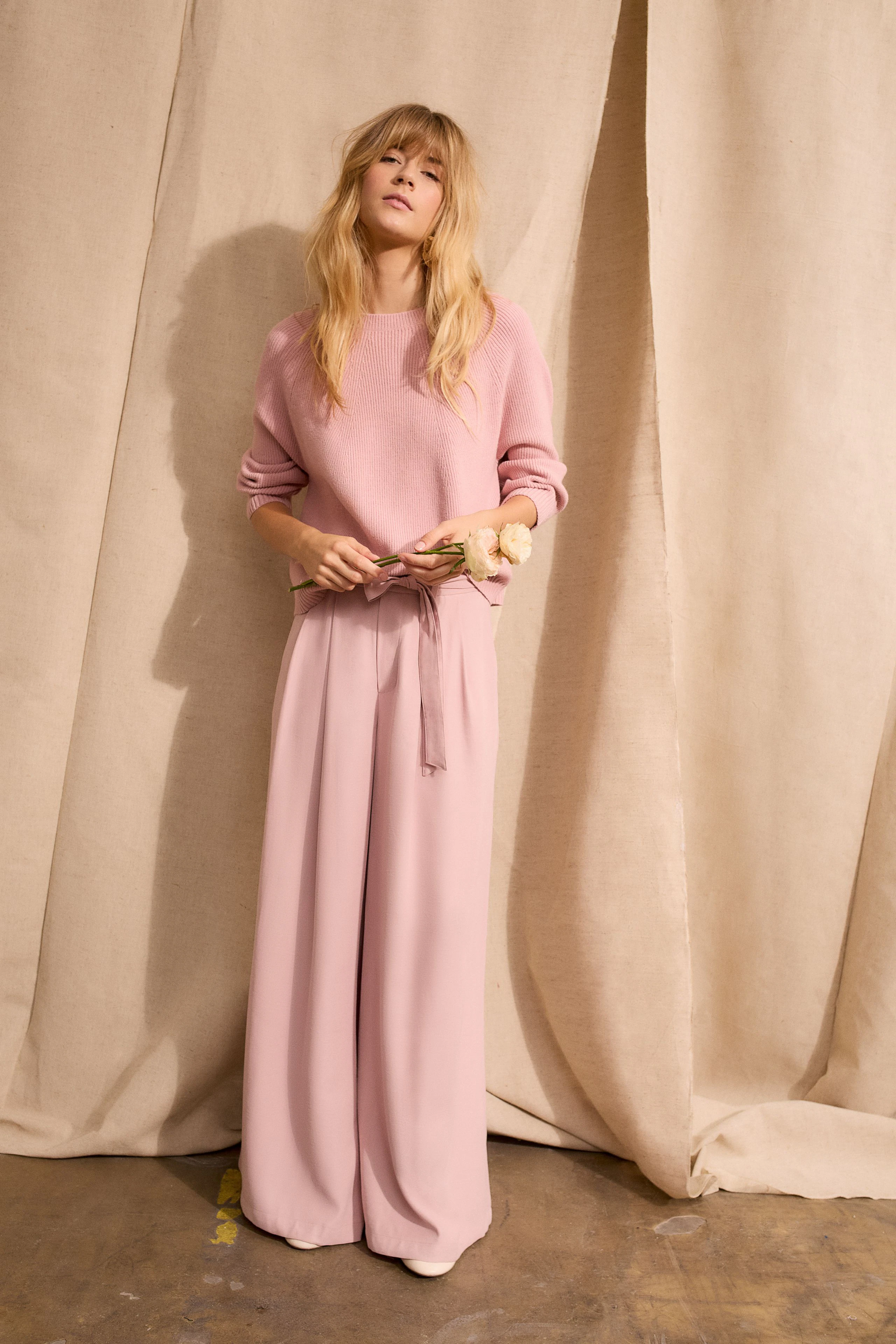 Damen-Pullover in zartem Rosa: Frau mit lässigem Look, kombiniert mit weiten Hosen.