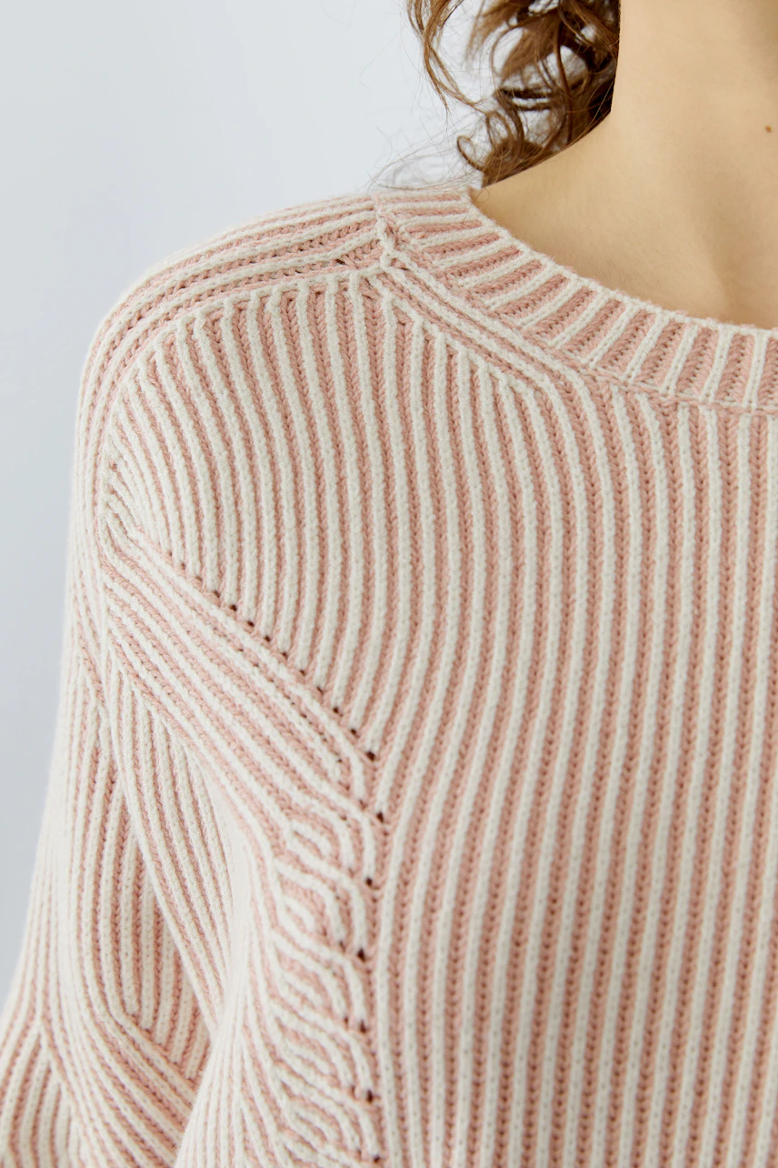 Casual women's pullover: Close-up of a woman in a pink striped pullover with a relaxed fit.