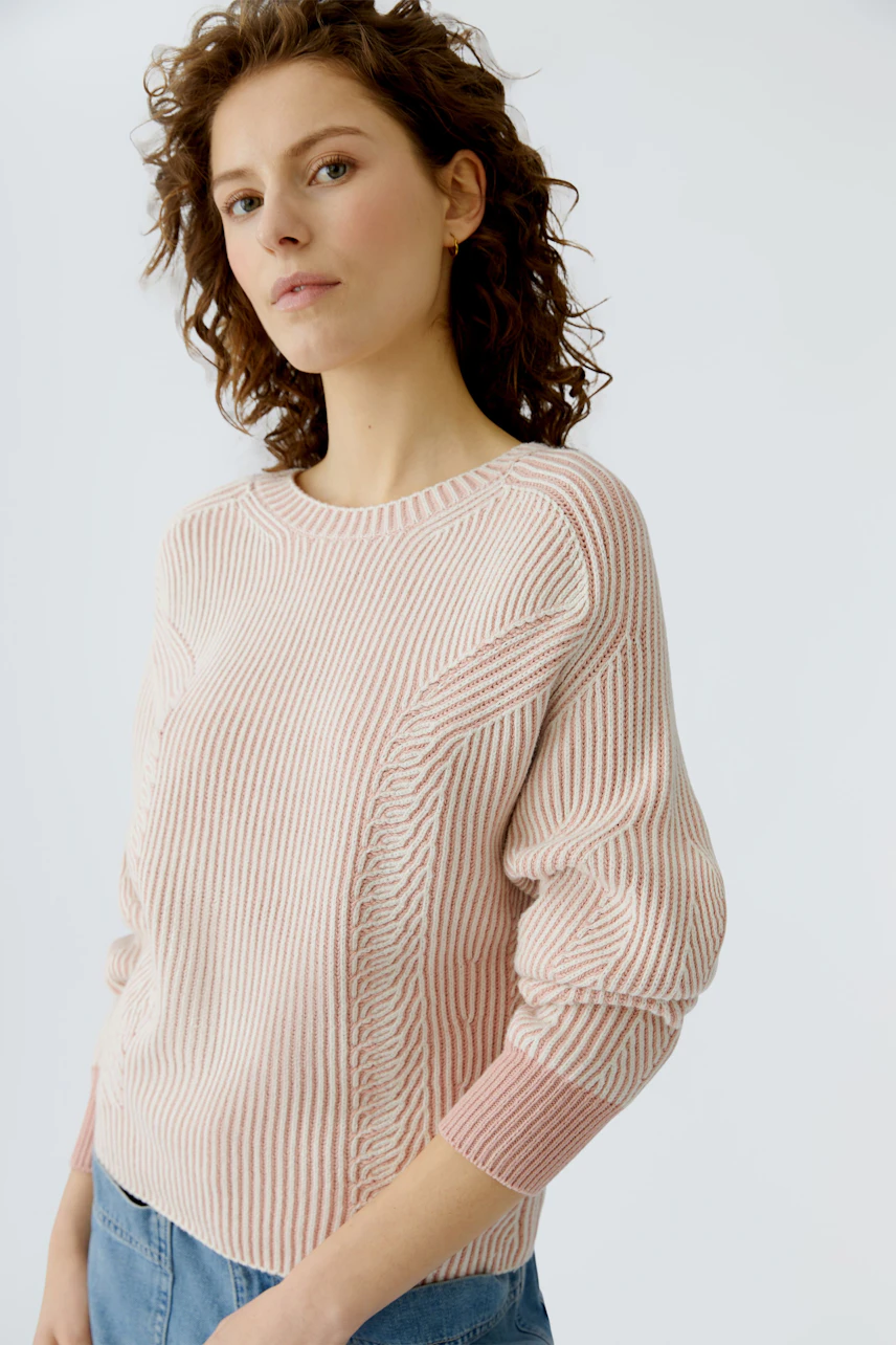 Casual women's pullover: Young woman in a pink striped pullover with relaxed fit and rolled sleeves.