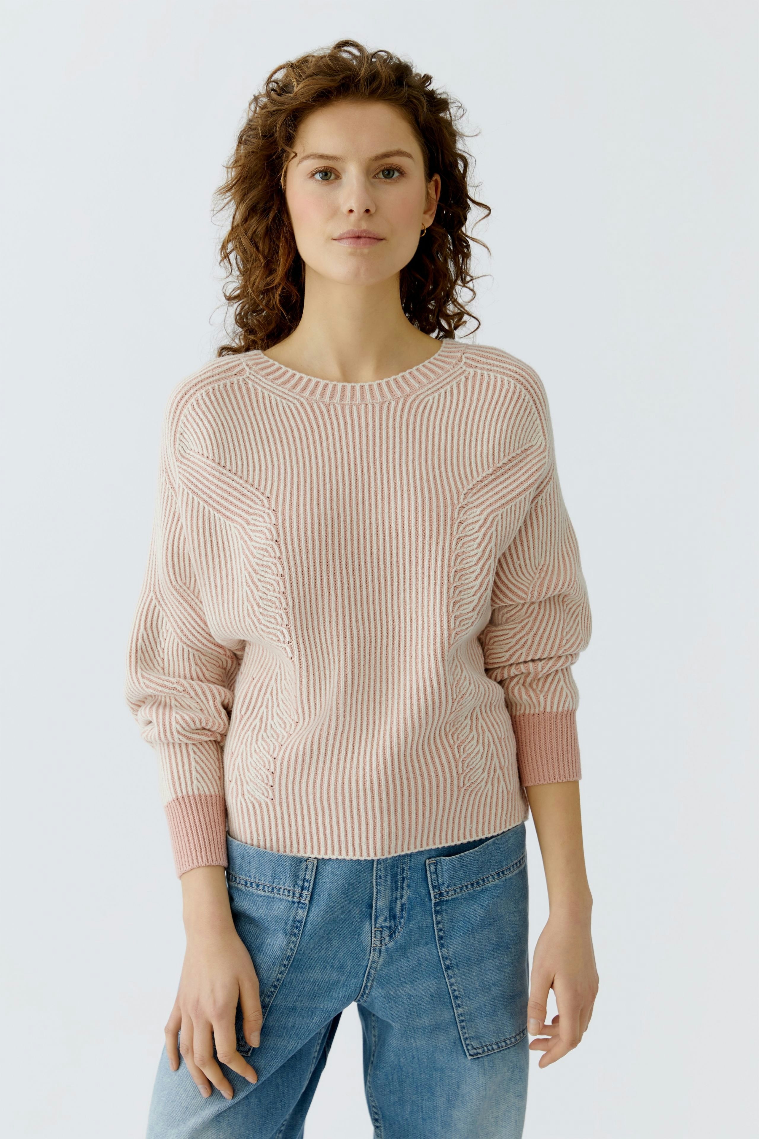 Casual women's pullover: A woman in a light pink ribbed pullover with relaxed fit and stylish details.