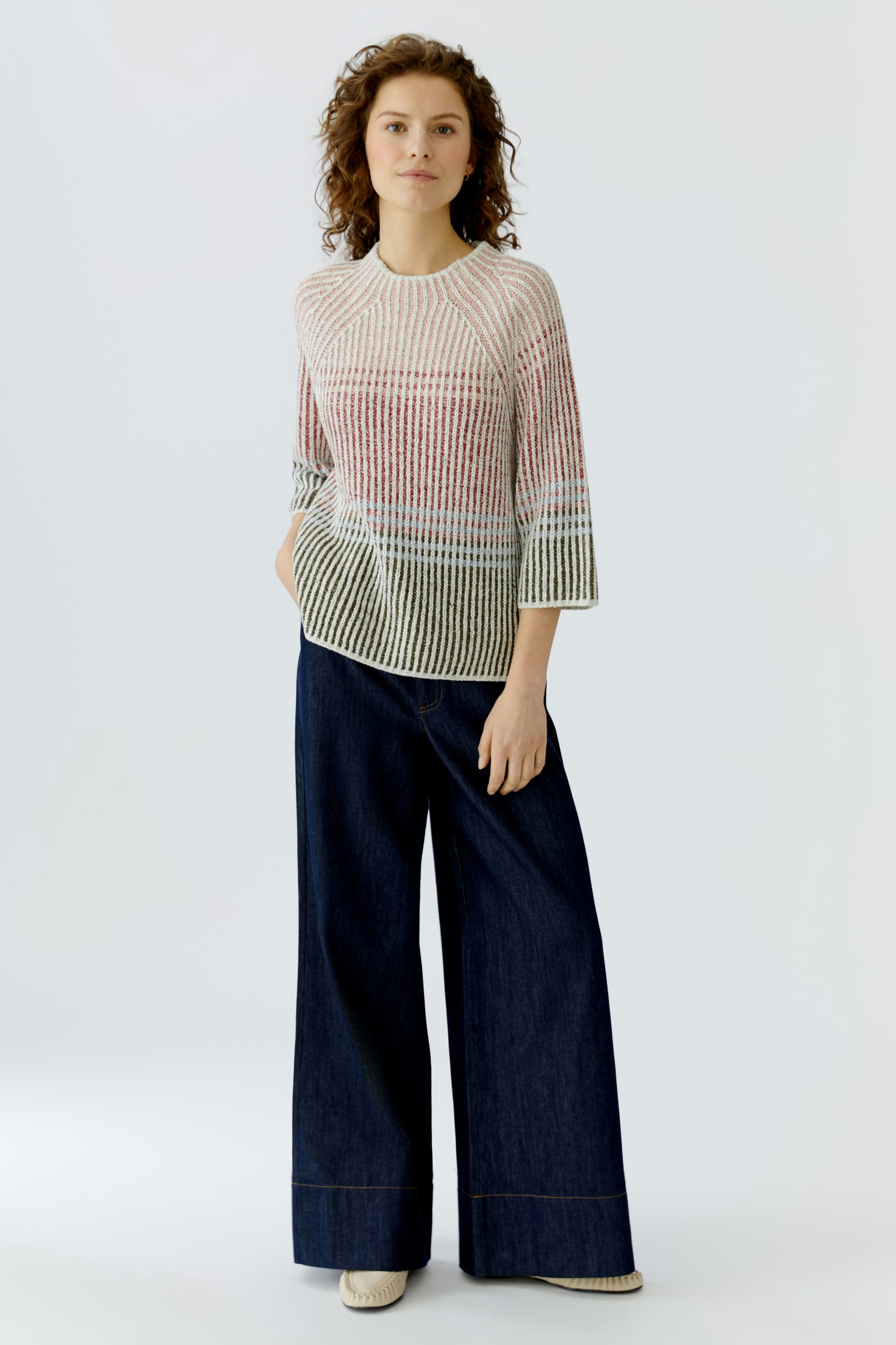 Casual women's pullover: Young woman in a colorful knit pullover paired with wide-leg jeans.