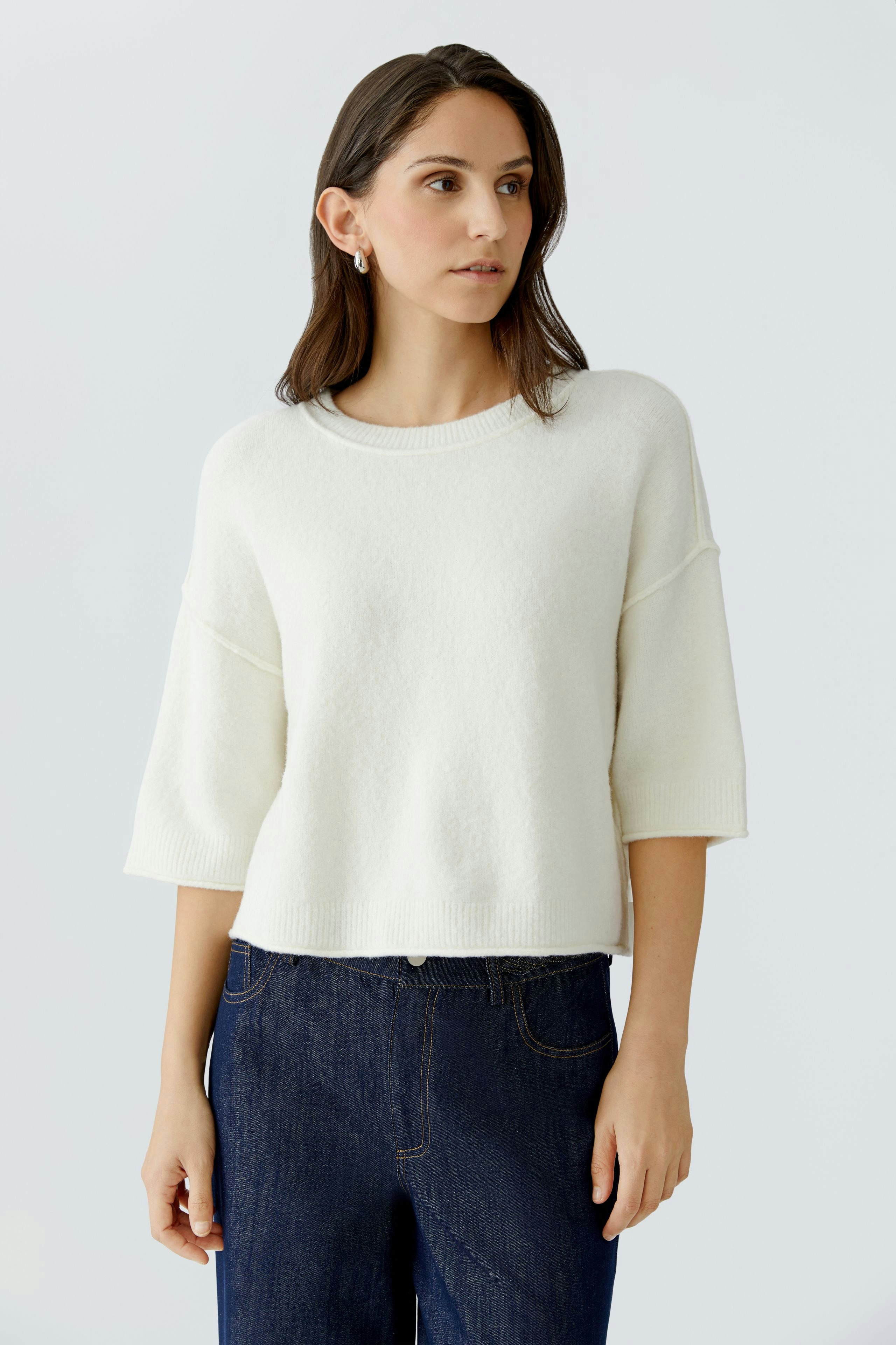 Casual women's pullover: A woman in a soft white pullover with wide sleeves and relaxed fit.