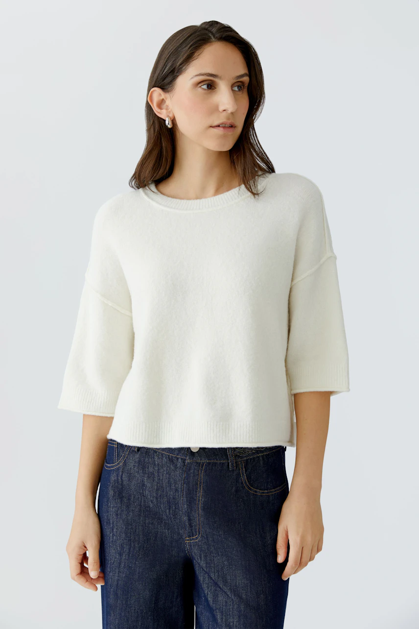 Casual women's pullover: A woman in a soft white pullover with wide sleeves and relaxed fit.