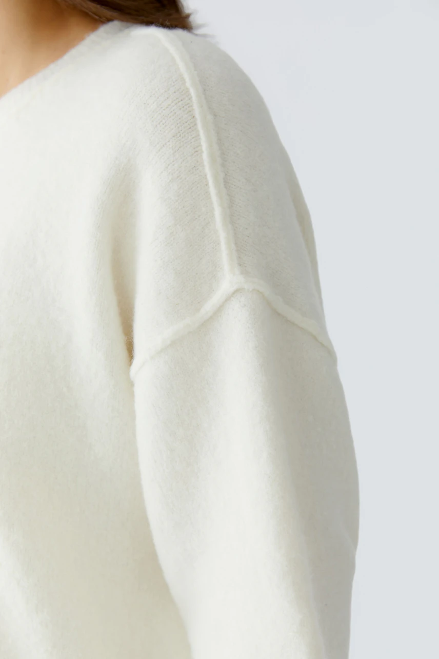 Casual women's pullover: Close-up of a woman wearing a soft, cream-colored pullover with relaxed fit.