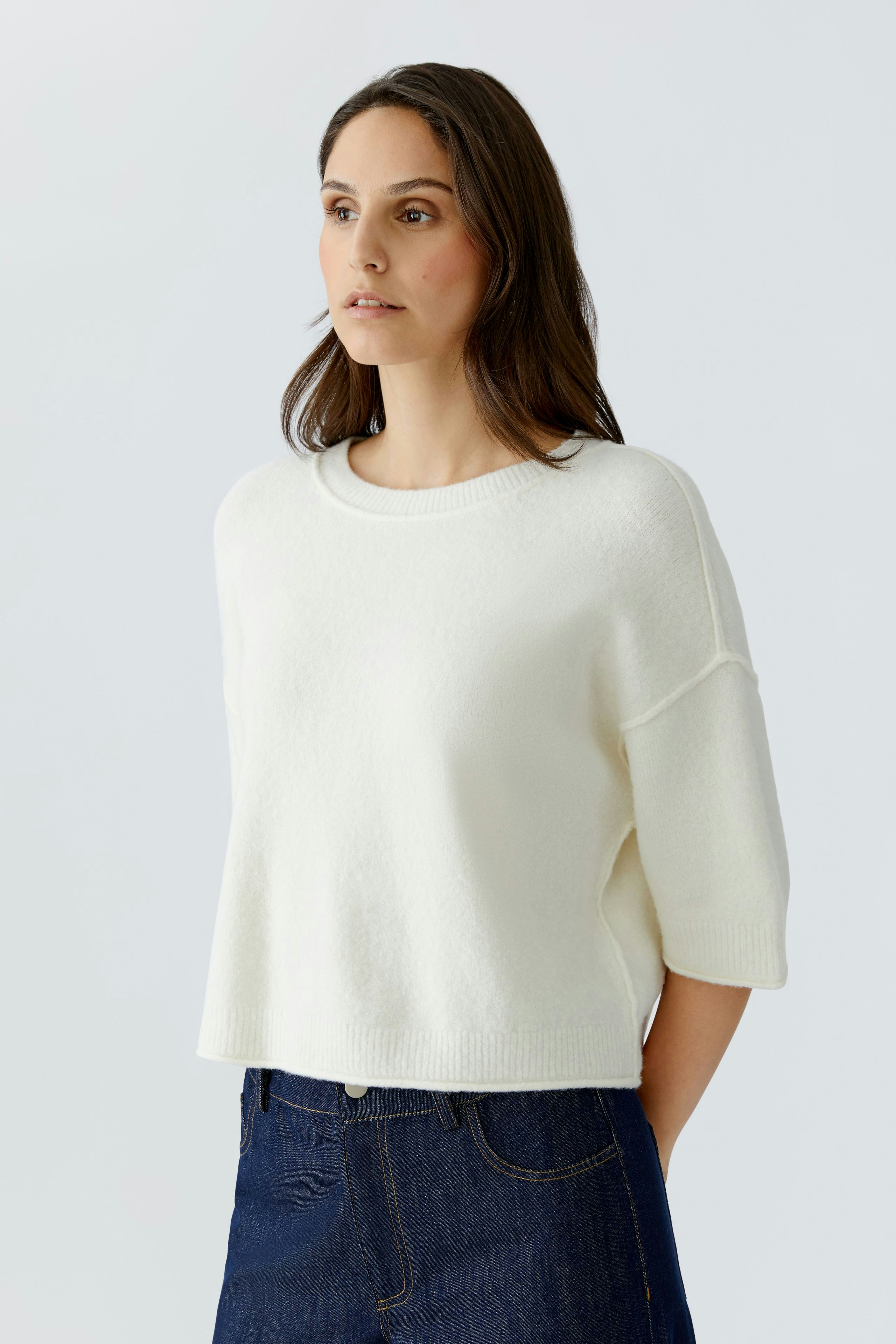 Casual women's pullover: A woman in a white, relaxed-fit pullover with short sleeves.