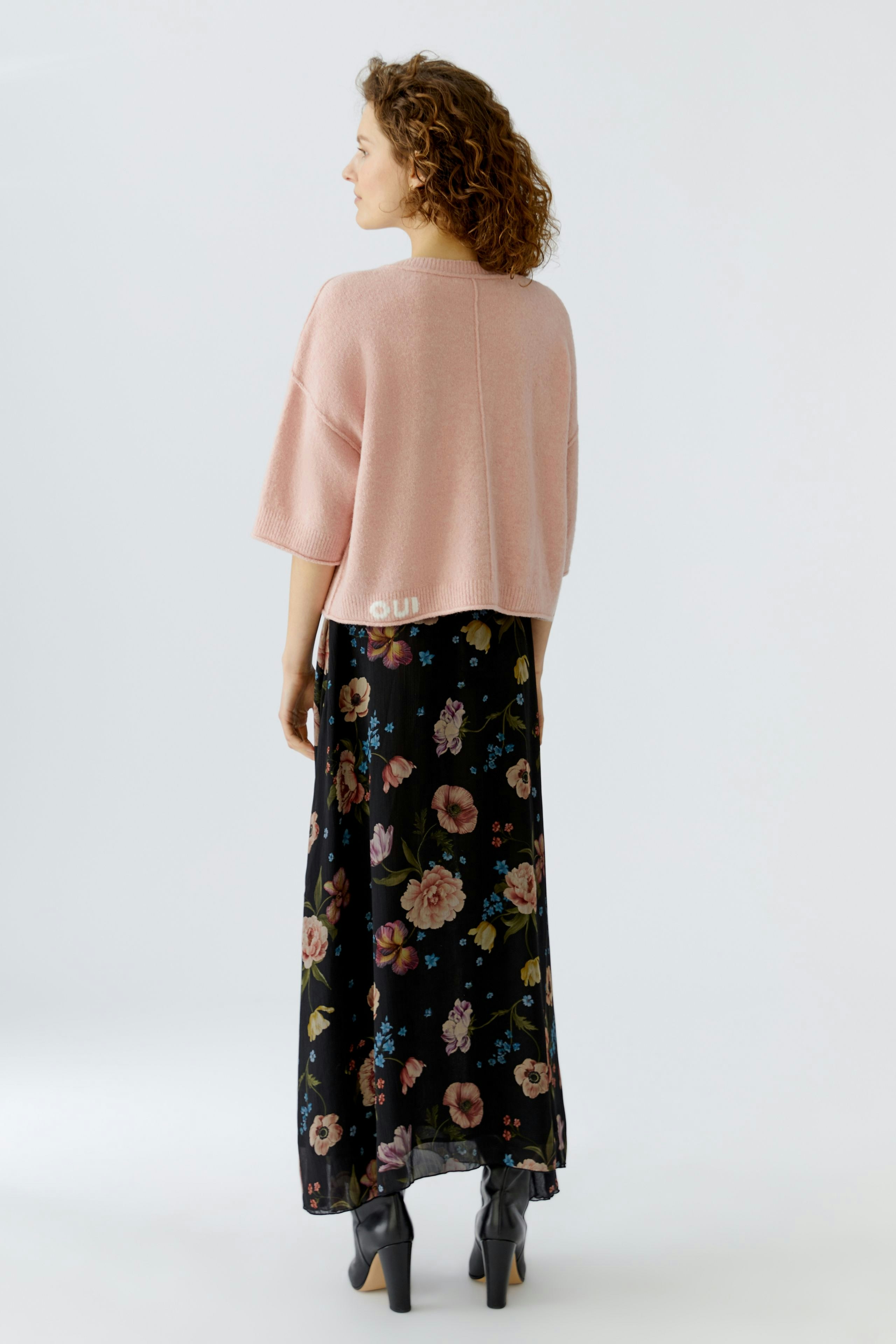 Casual women's pullover: A woman in a pink pullover with short sleeves, paired with a floral skirt.