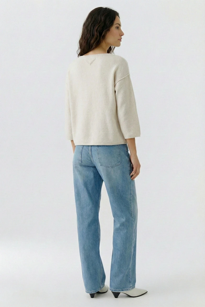 Bequemer Damen-Pullover in hellem Beige, lässig kombiniert mit blauen Jeans, von hinten sichtbar.