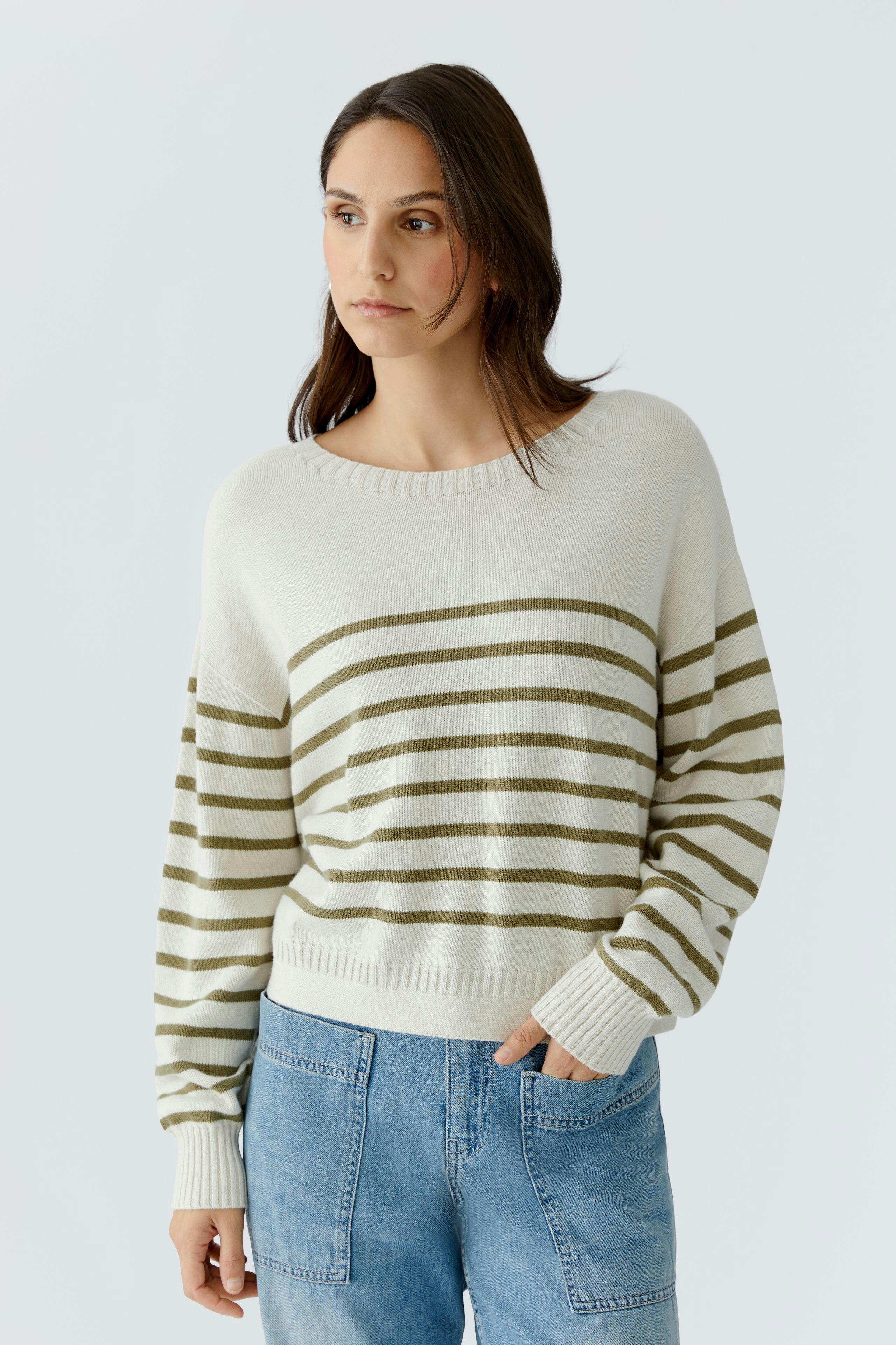 Casual women's pullover: A woman in a striped pullover with green and white lines, paired with denim.