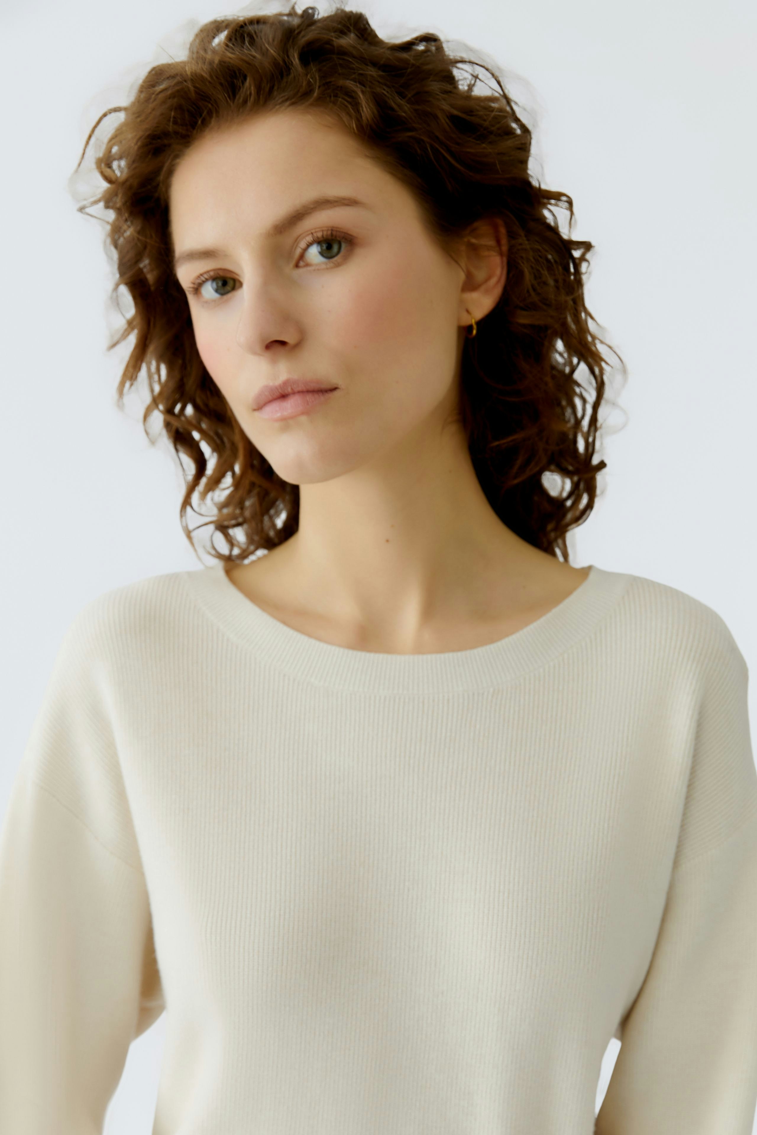 Modern women's pullover: A woman in a light beige pullover with a relaxed fit and round neckline.