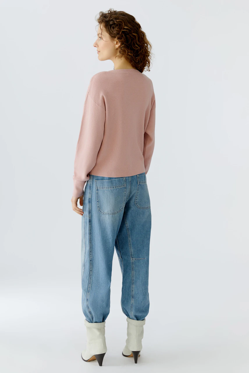 Casual women's pullover: A woman in a pink pullover paired with relaxed blue jeans, showcasing a laid-back style.