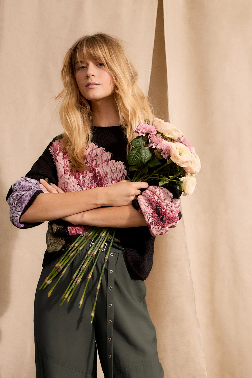 Damen-Pullover: Frau mit buntem Strickpullover und Blumenstrauß, lässig und modern.