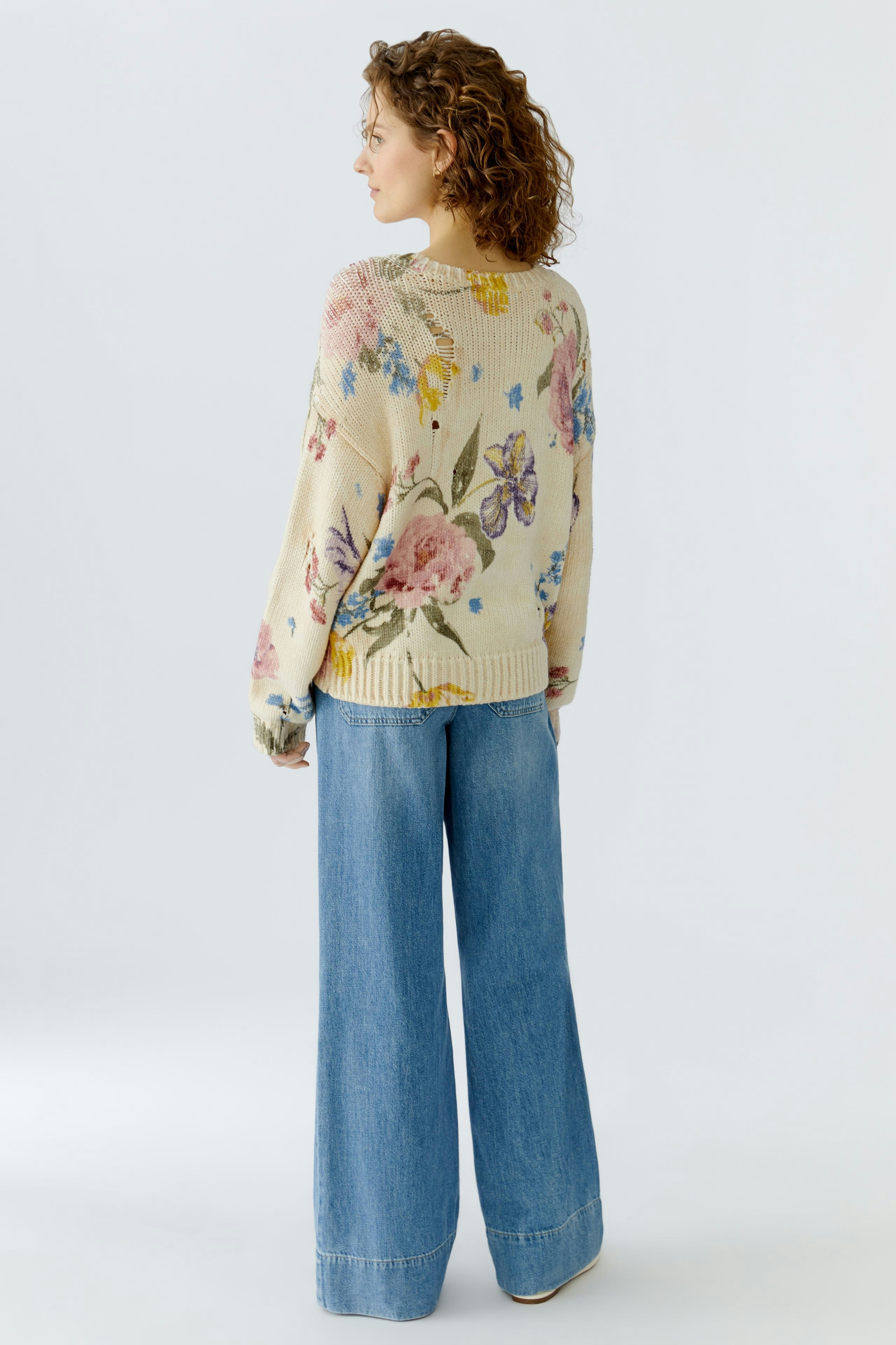 Casual women's pullover: A woman in a floral knit pullover paired with wide-leg jeans, showcasing a relaxed style.