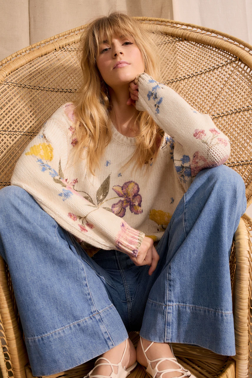 Casual women's pullover: Young woman in a floral knit pullover, relaxed pose, wearing wide-leg jeans.