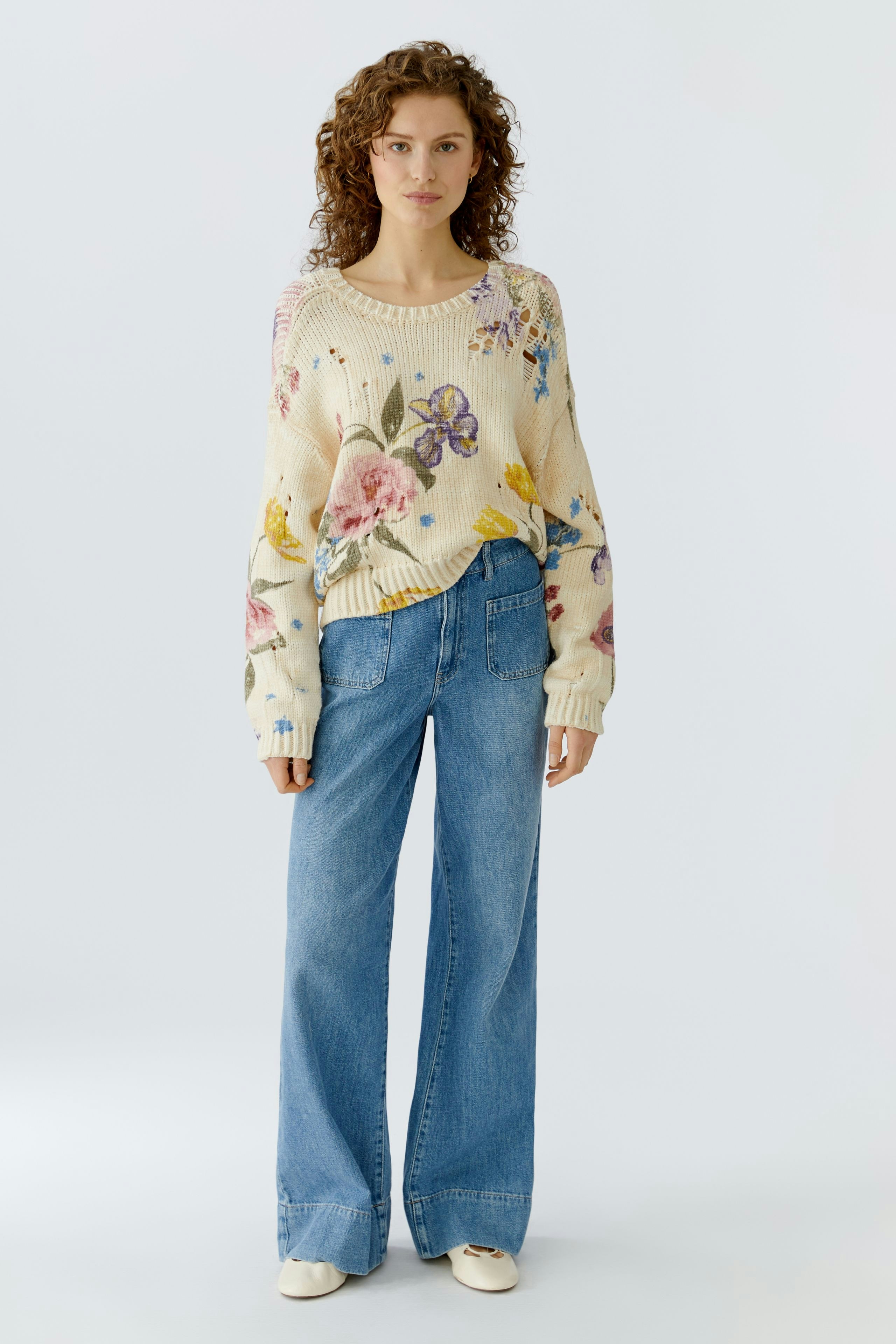 Casual women's pullover: A woman in a floral knit pullover paired with wide-leg jeans.