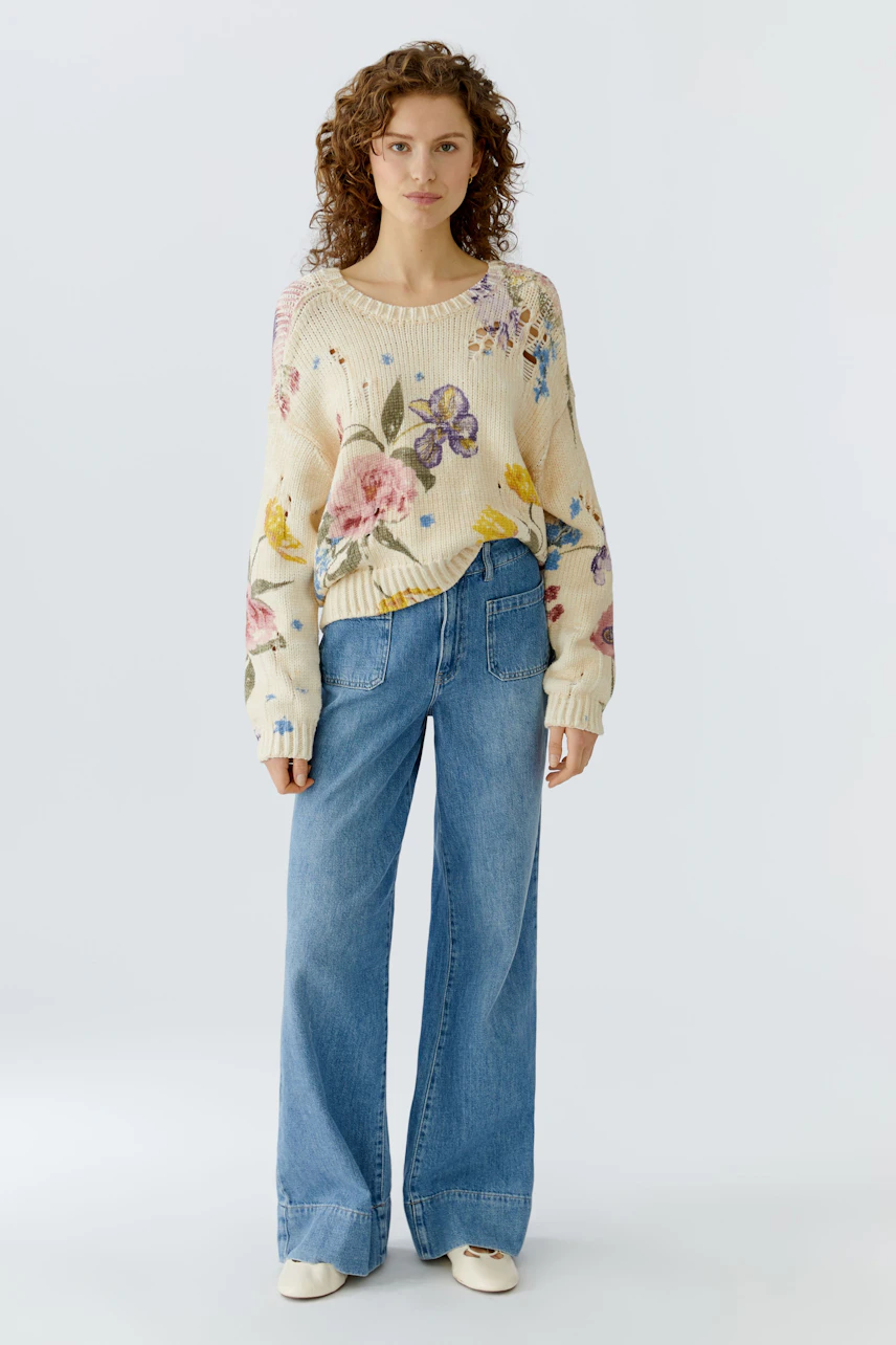 Casual women's pullover: A woman in a floral knit pullover paired with wide-leg jeans.