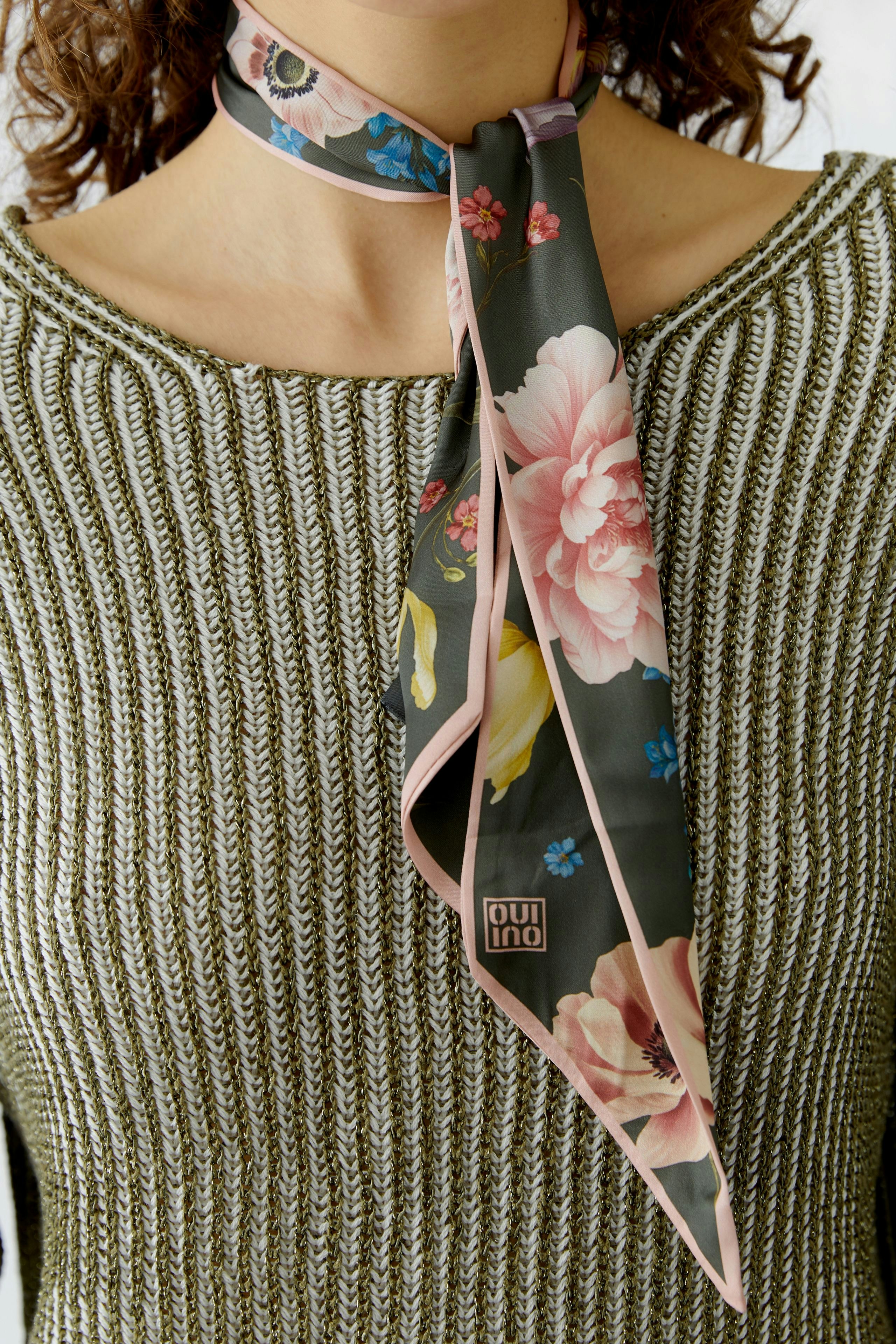Stylish women's scarf: A woman wears a floral-patterned scarf tied around her neck.