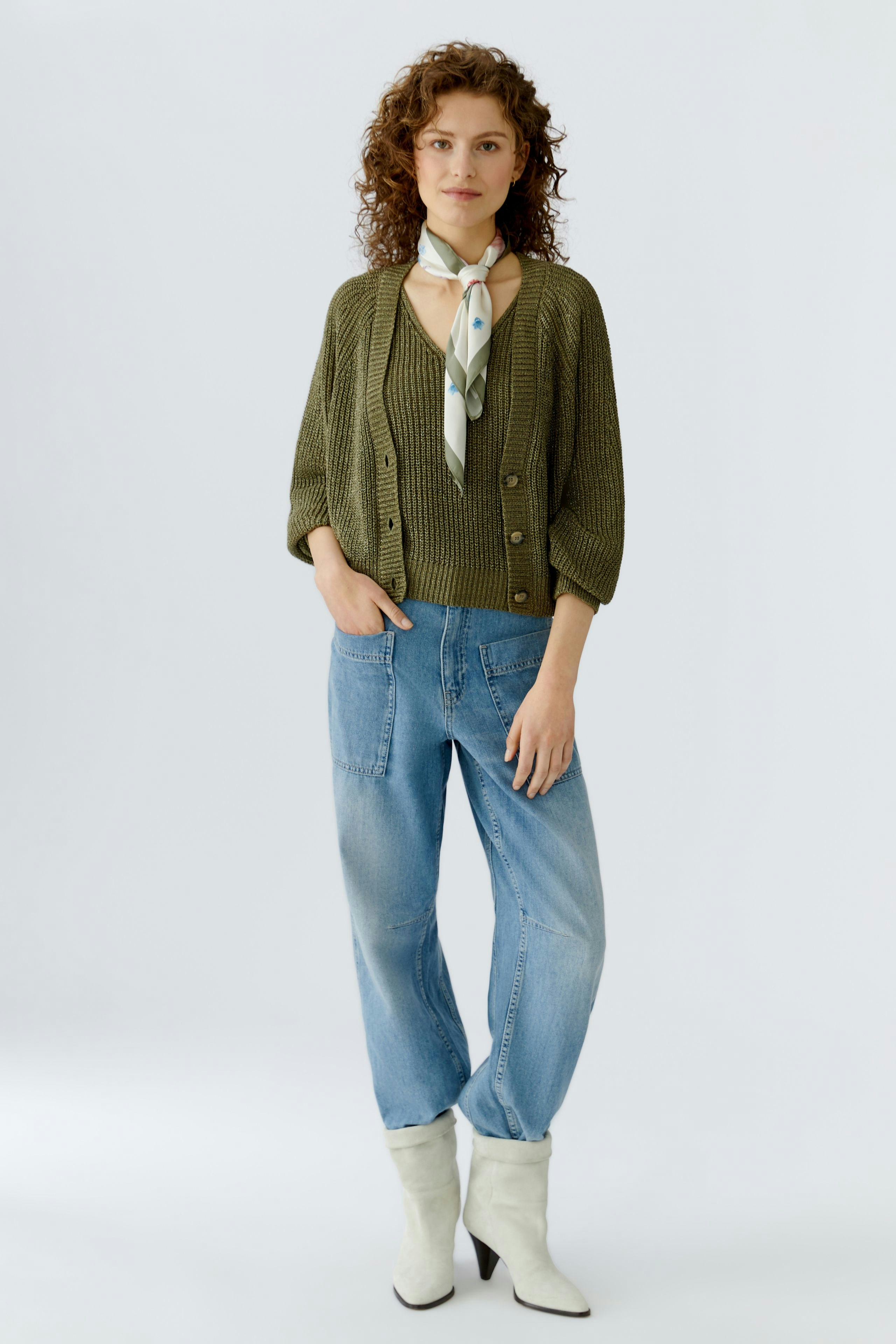 Casual women's scarf: A woman wearing a light green scarf tied around her neck, paired with a knitted cardigan.