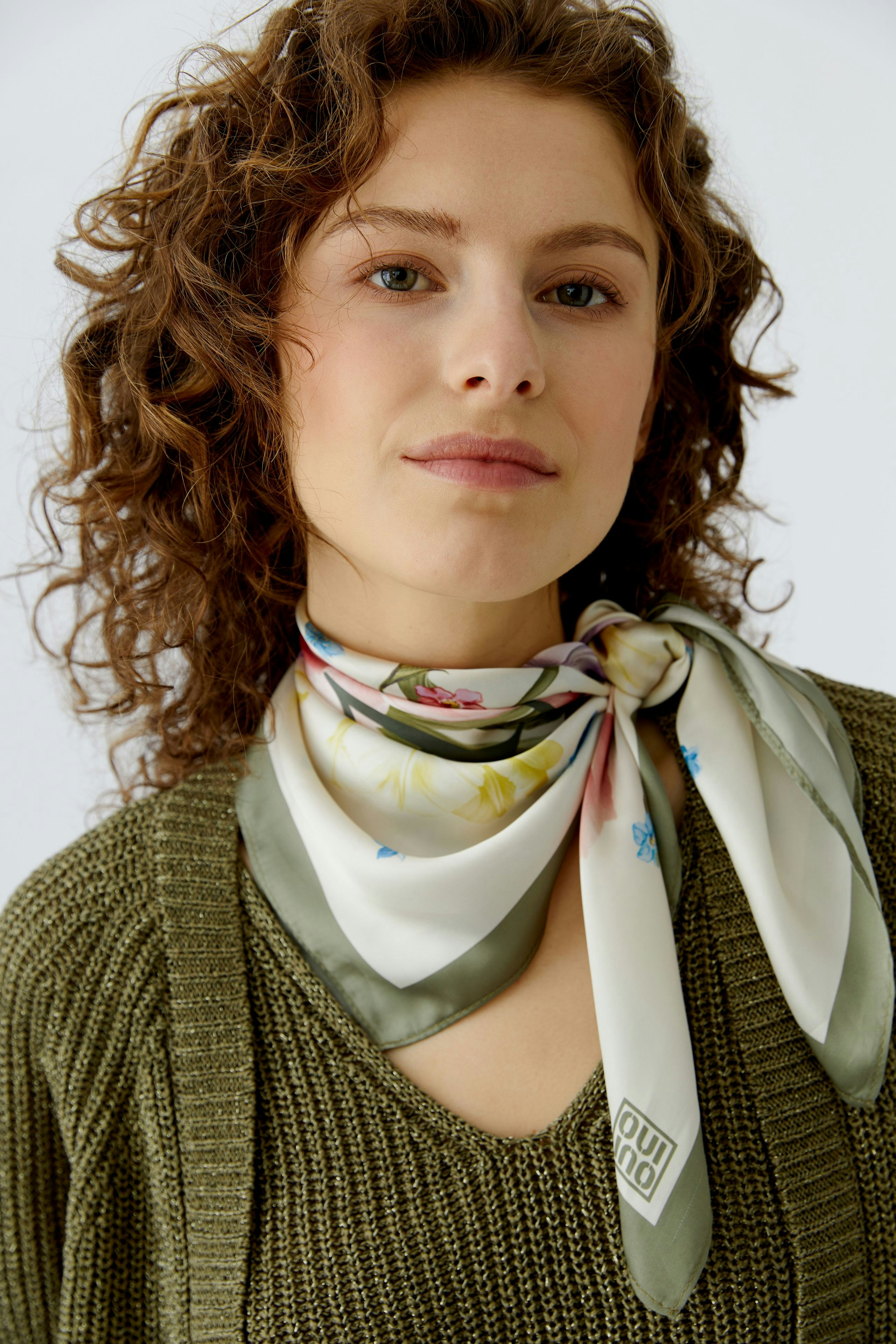 Stylish women's scarf: A woman wears a floral-patterned scarf tied around her neck, adding a fresh touch.