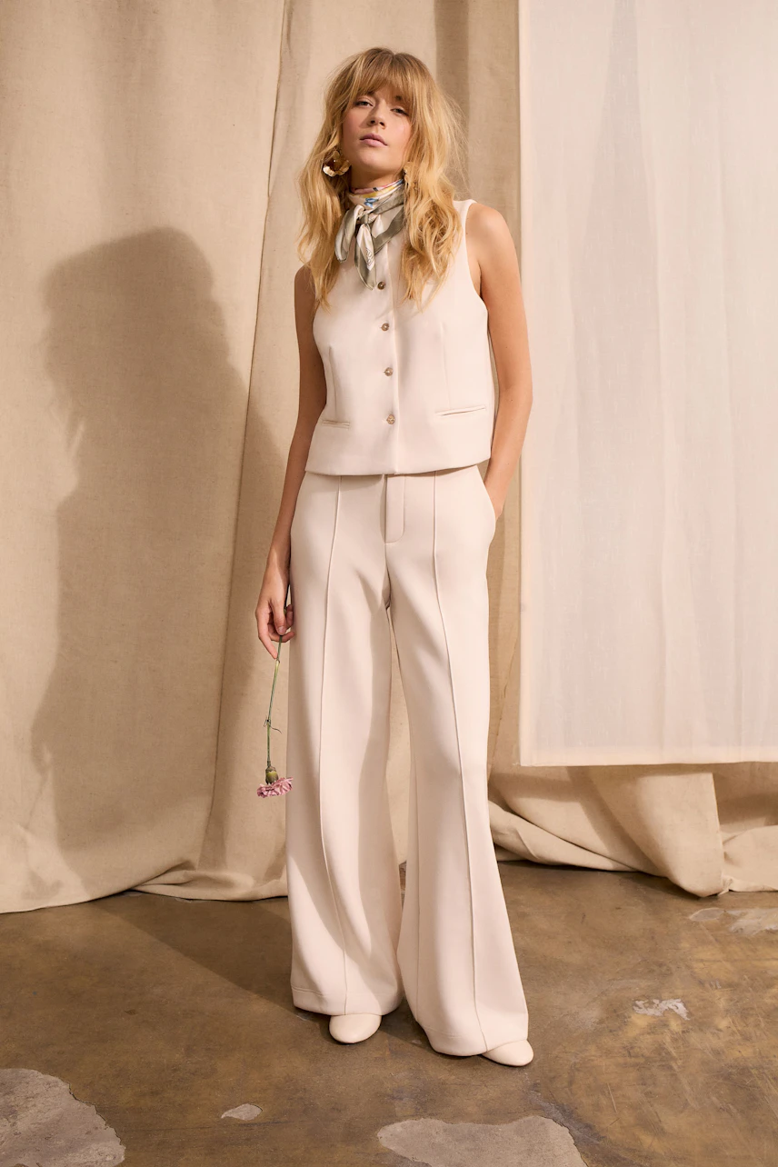 Damen-Tuch: Frau mit einem modischen Tuch in sanften Farben, kombiniert mit einem ärmellosen Oberteil und Hose.