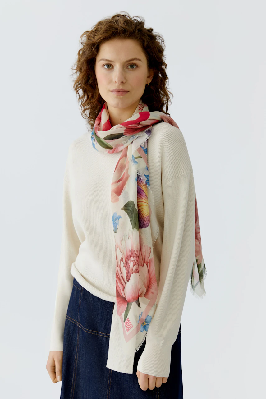 Stylish scarf: Woman wearing a floral scarf over a light pullover, adding a fresh touch to her outfit.