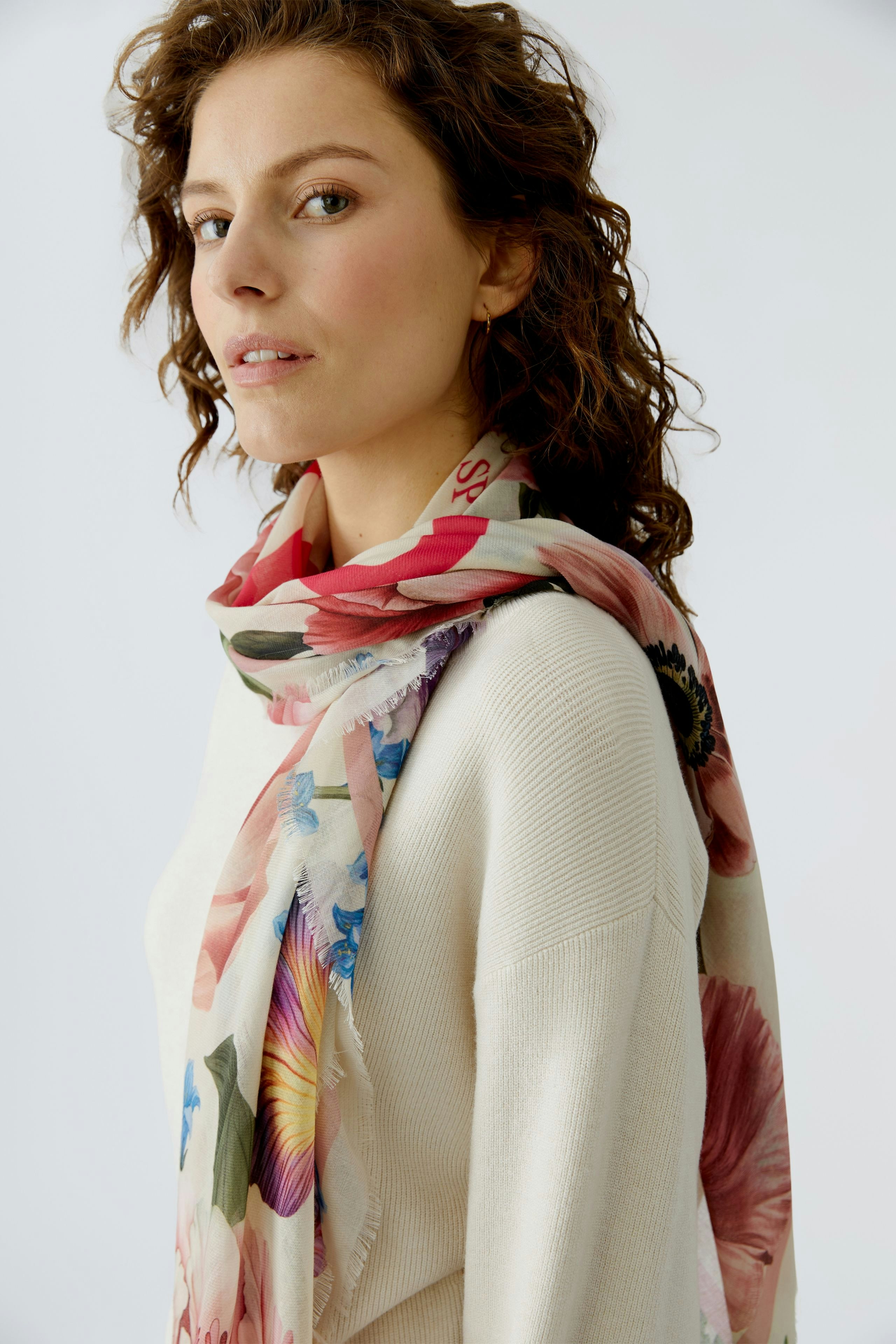 Stylish scarf: Woman wearing a floral scarf with vibrant colors, adding a fresh touch to her outfit.