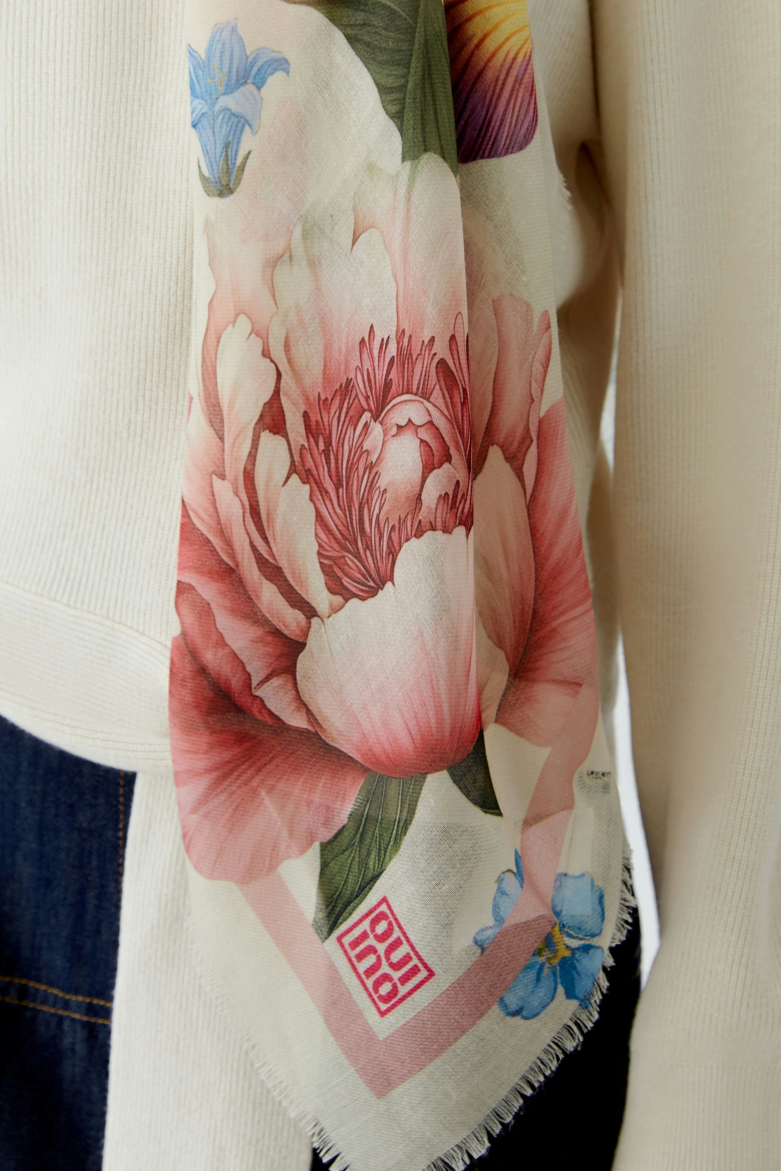 Colorful scarf featuring floral patterns, worn by a woman, adding a vibrant touch to any outfit.