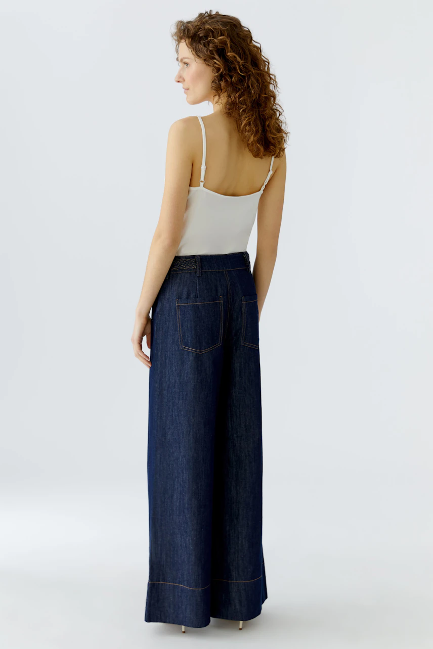 Wide leg jeans: Woman in dark blue wide leg jeans and a simple white top, showcasing a relaxed fit.