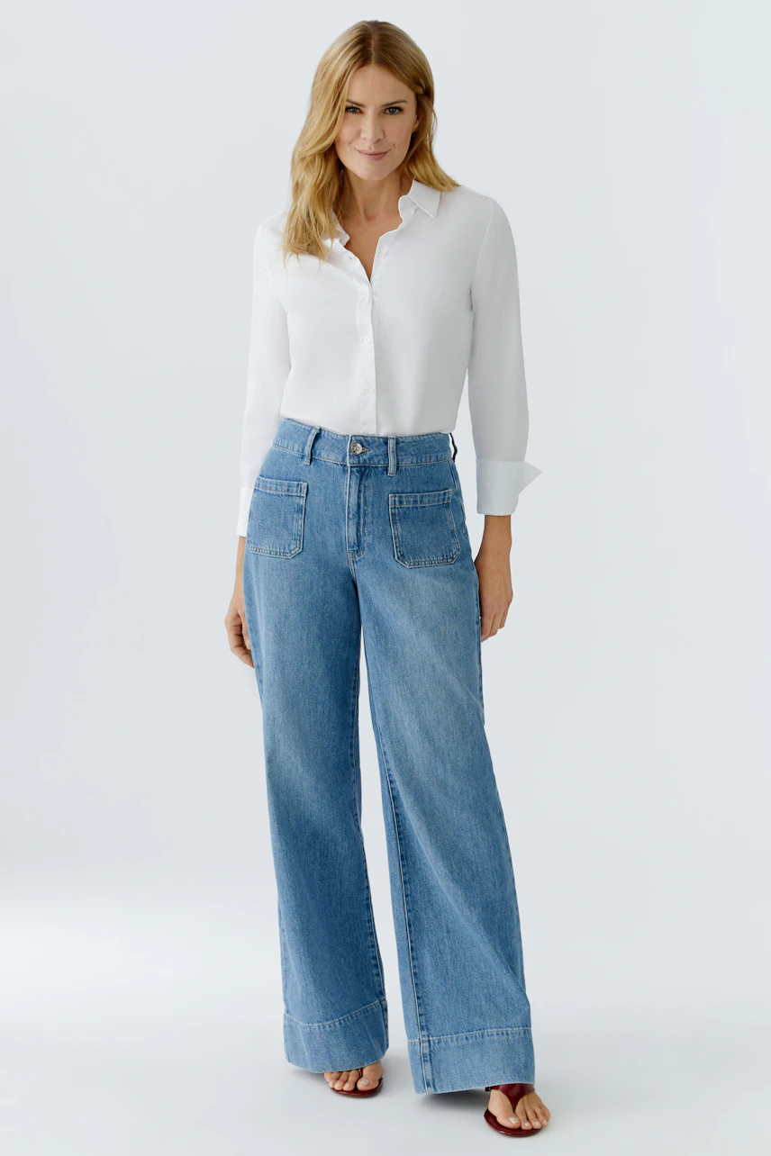 Damen Jeans Wide Leg: Frau in lässigen, weiten Jeans mit hellem Oberteil und Sandalen.