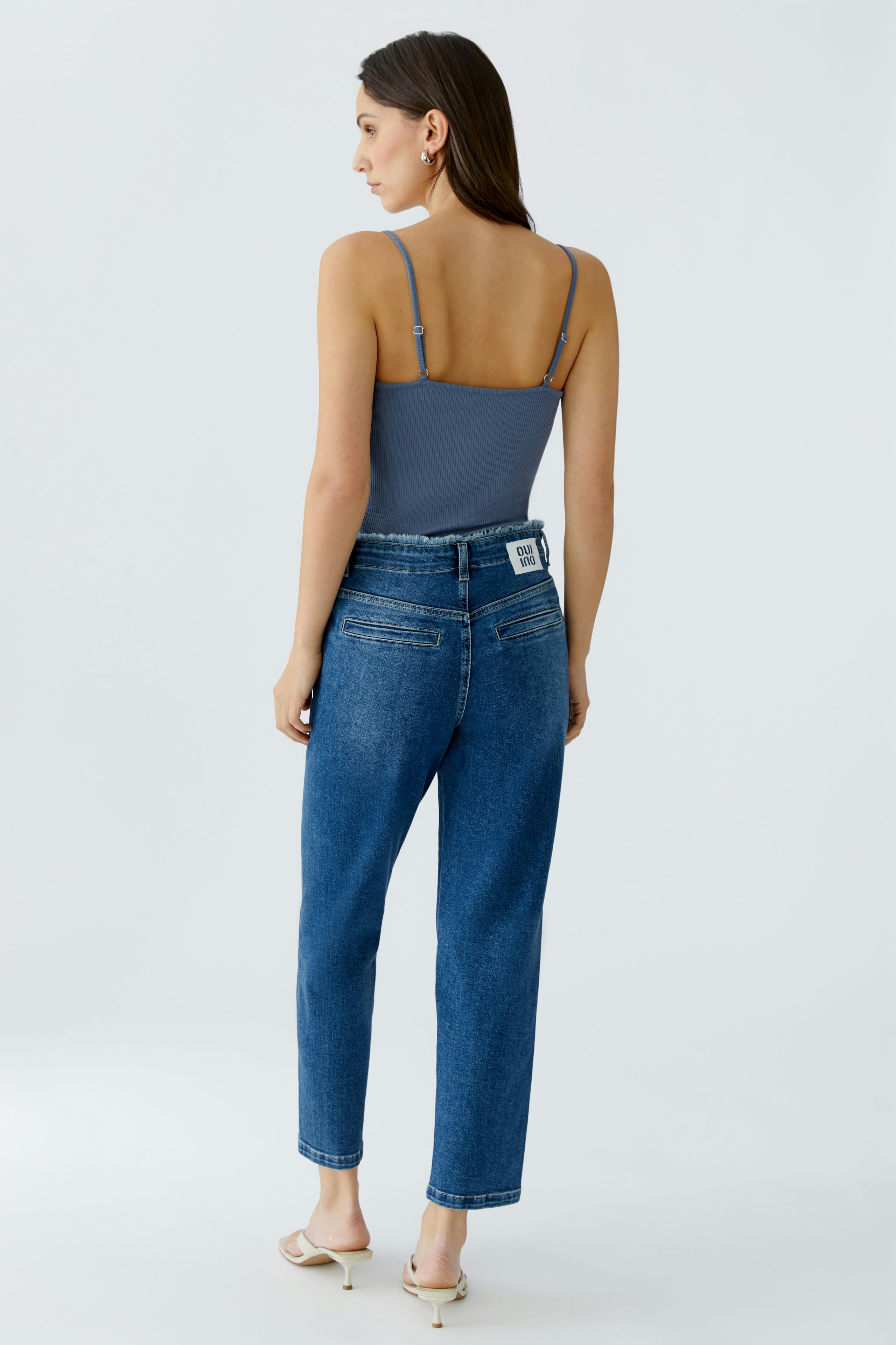 Tapered jeans for women: A woman in blue tapered jeans with a fitted top, showcasing a casual look.
