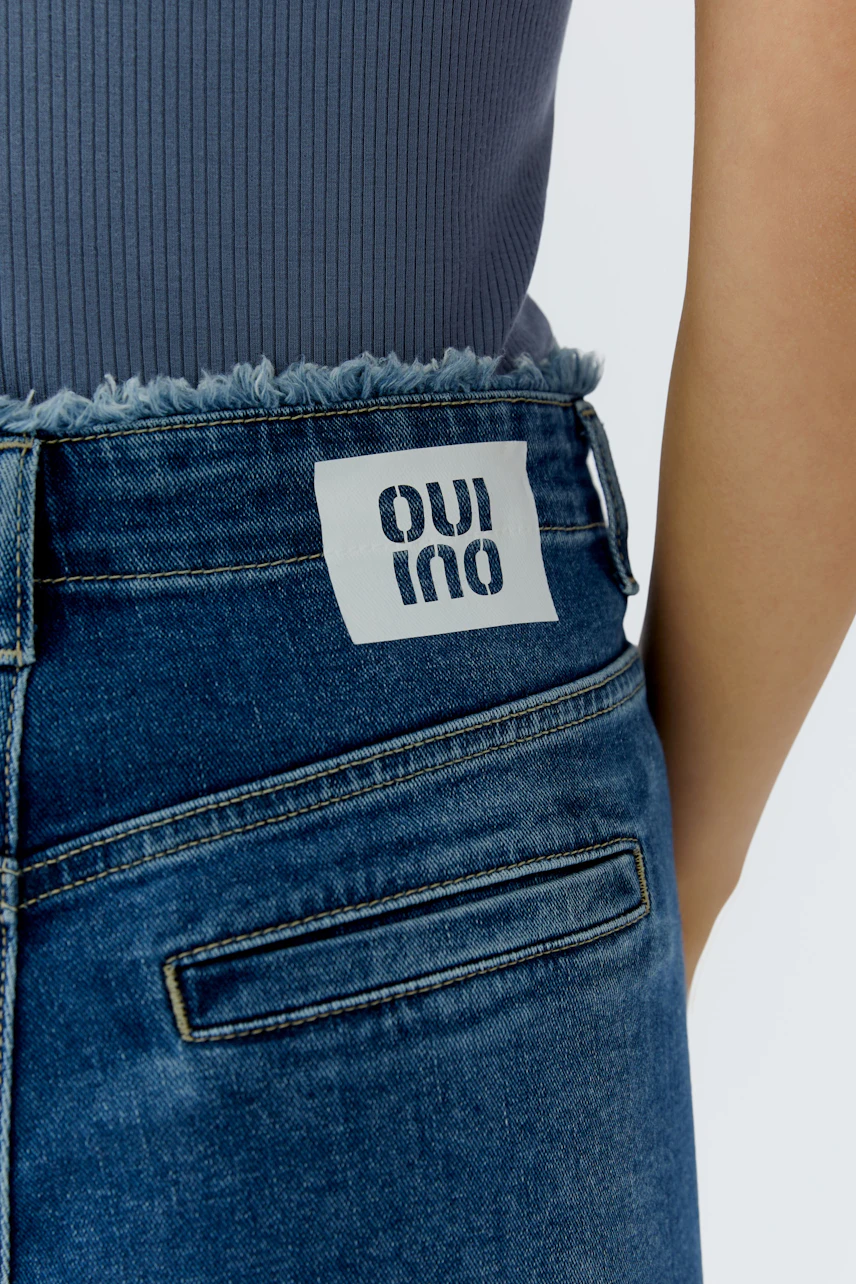 Tapered jeans: A woman shows off her casual style with these trendy blue jeans featuring a frayed hem.