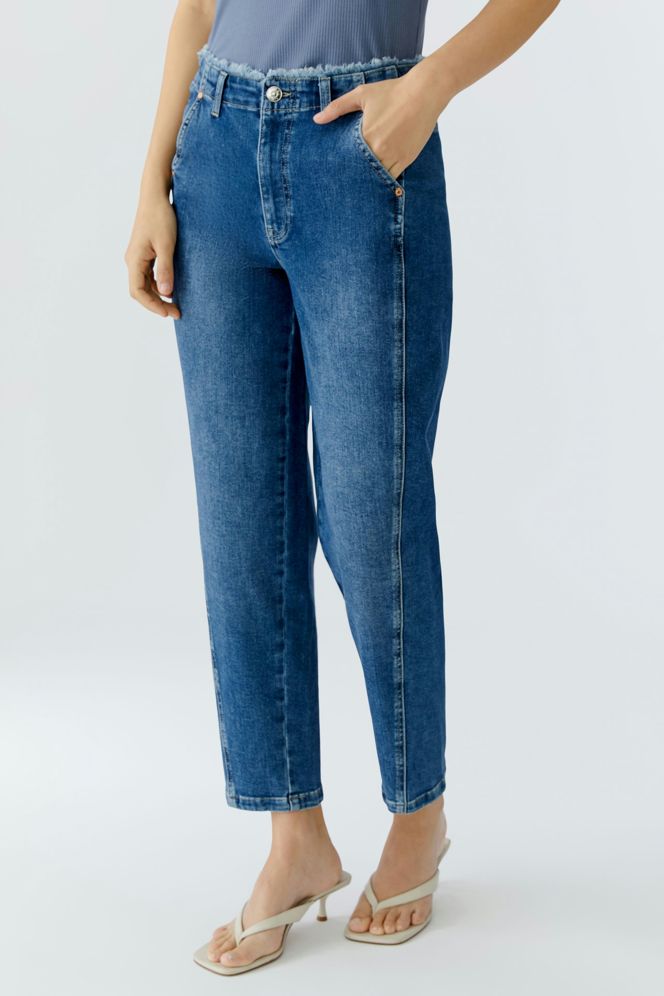Tapered jeans for women: A woman in blue tapered jeans stands confidently, showcasing a casual style.