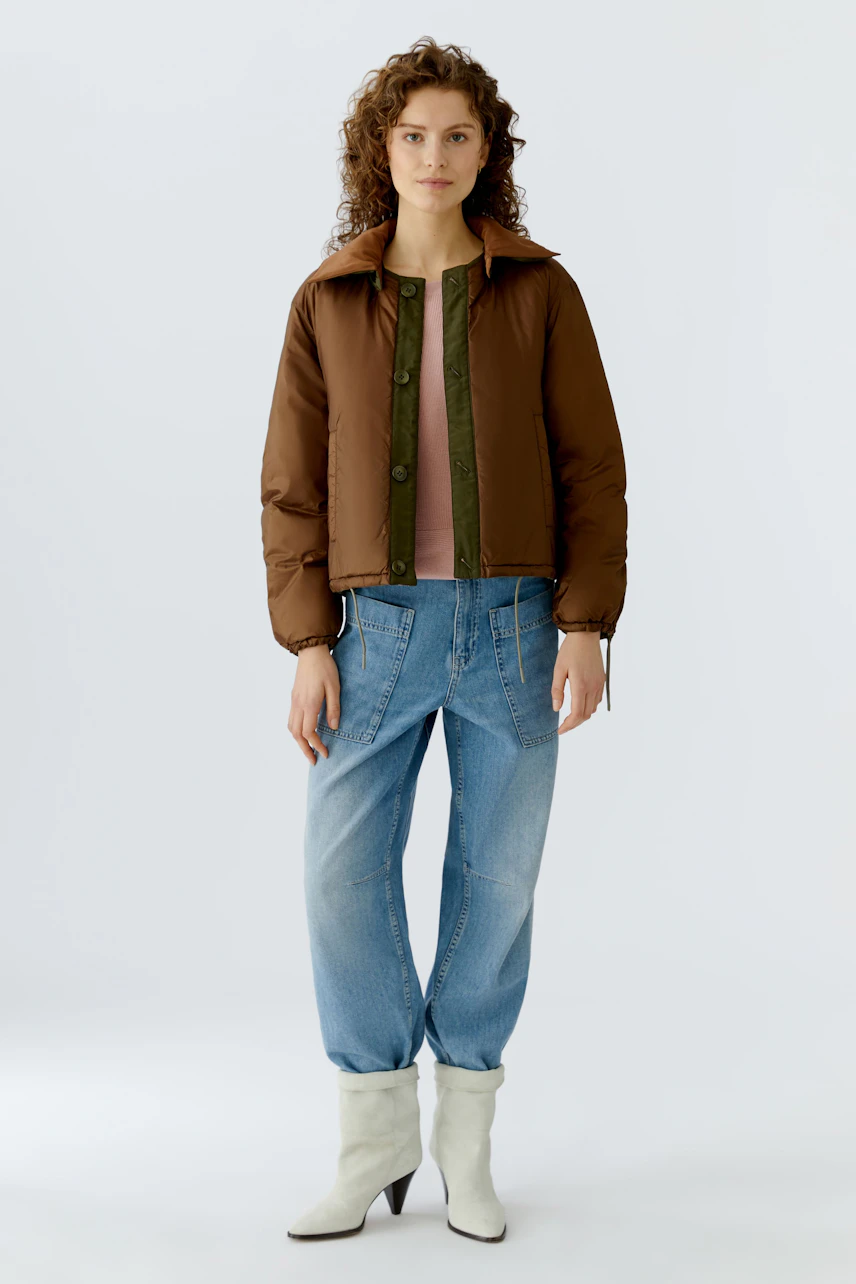 Wendejacke: Junge Frau in brauner Wendejacke mit lässigen Jeans und Stiefeln.