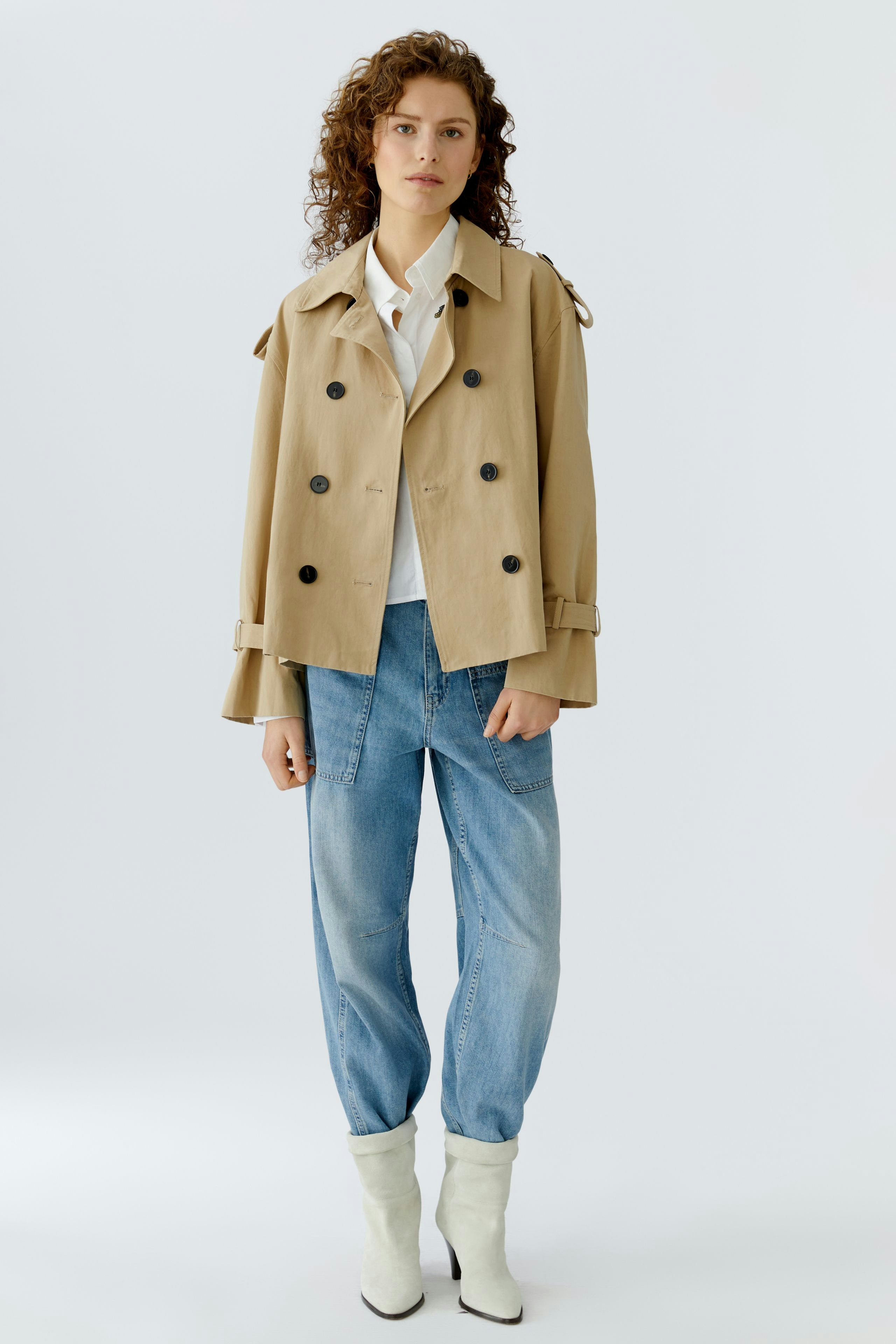 Stylish women's jacket: A woman in a beige double-breasted jacket paired with relaxed jeans.